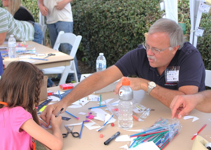 ATA’s Marvin Sellers assists a student as she constructs a straw rocket in the AAPS booth at the Polly Crockett Festival. (Photo provided)