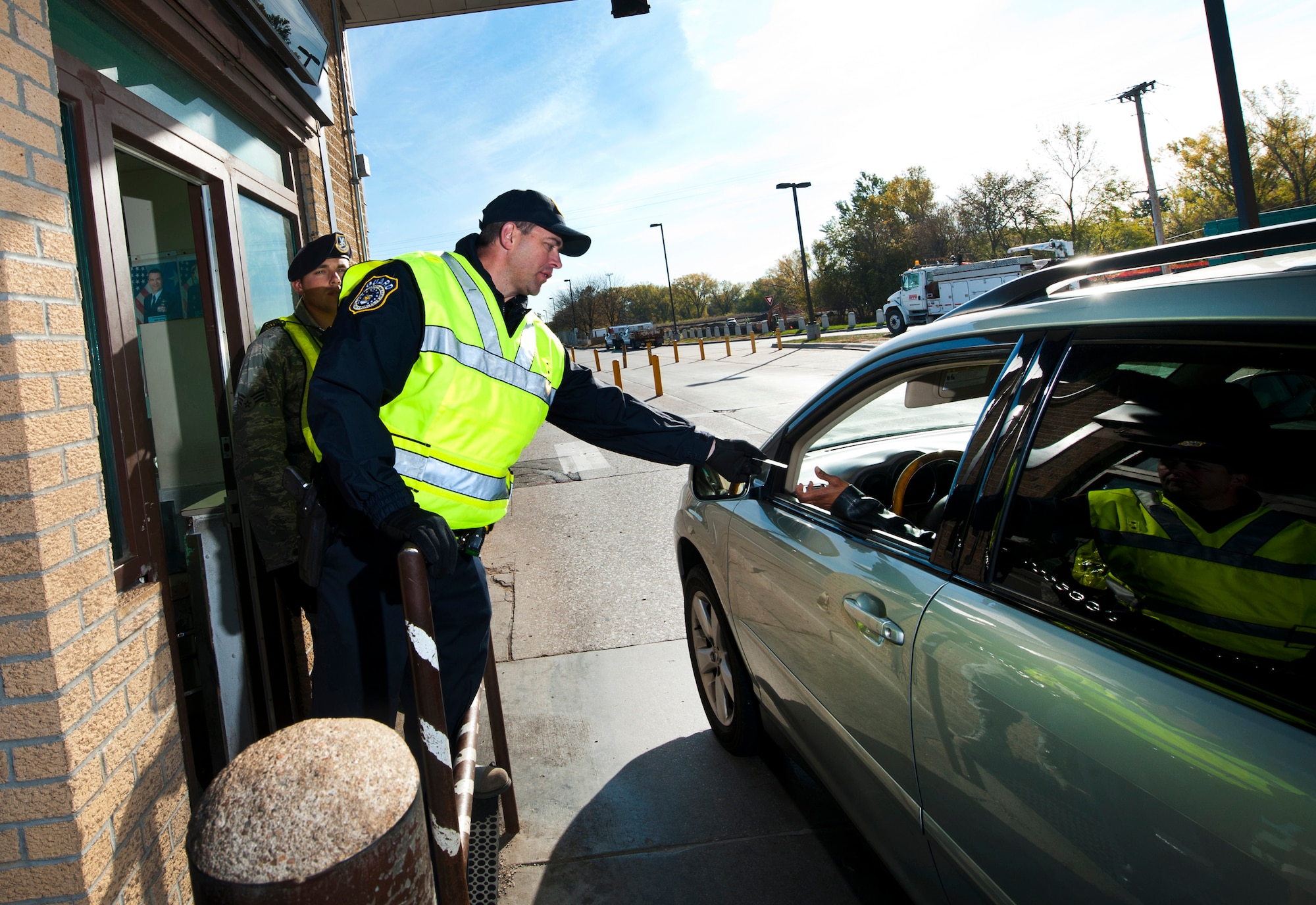 Dan Grove, a Department of the Air Force civilian police officer with the 55th Security Forces Squadron, keeps traffic moving through the U.S. Strategic Command gate as he checks identification cards at Offutt Air Force Base, Neb., Oct. 24. The 55 SFS is currently transitioning from contract gate guards to DAF civilian police officers. (U.S. Air Force photo by Josh Plueger/Released)