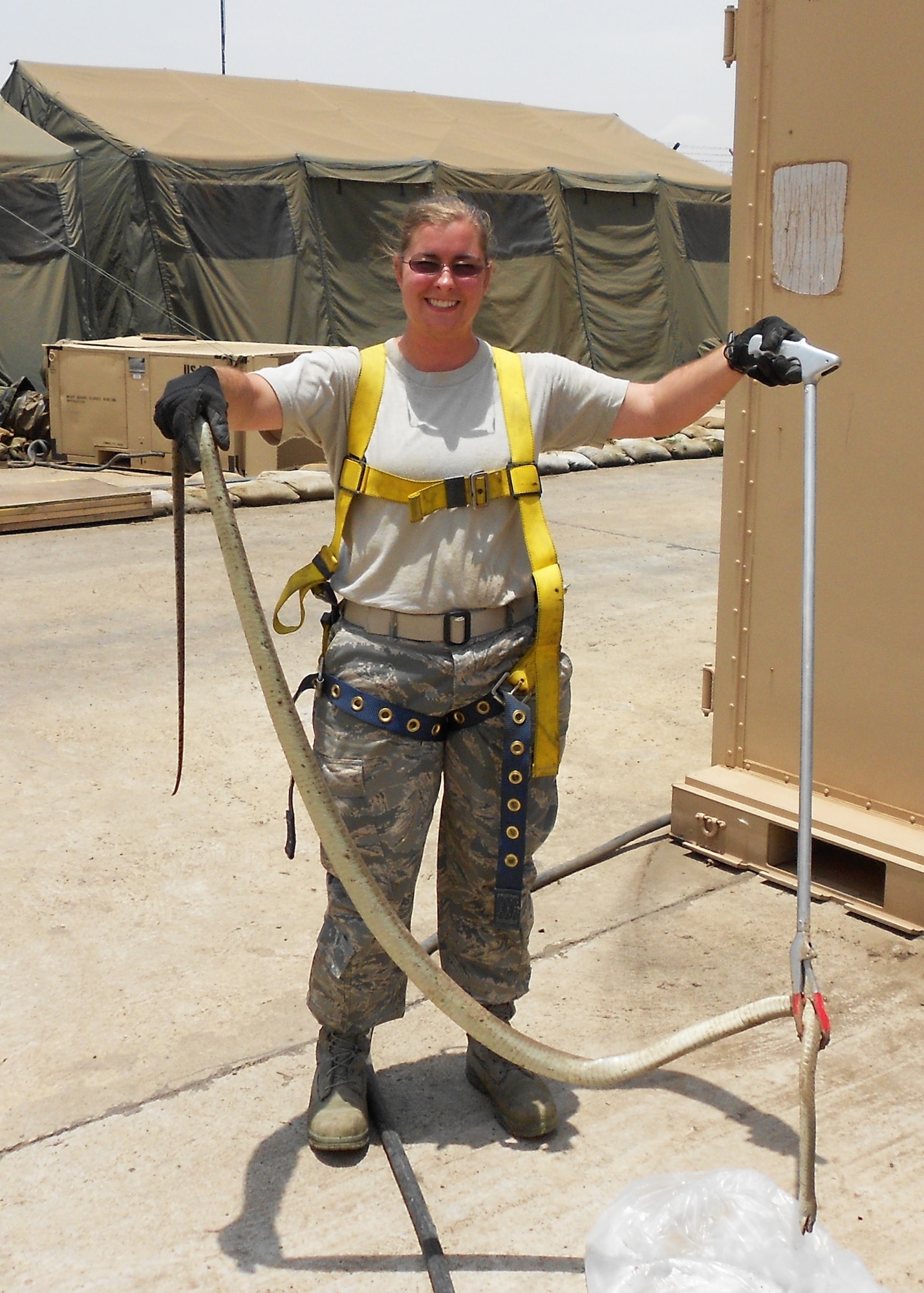 Air Force Reserve Master Sgt. Jennifer Alexander displays a highly venomous black mamba she helped remove from a tree at an entrance to her deployed location.  In her duties as the deployed pest control manager for a U.S. Africa Command forward operating base, the Duke Field civil engineering Airman often works with host nation military officials to eliminate dangerous wildlife hazards and ensure non-threatening wildlife found on and near her base are safely returned to the wild. (Courtesy photo)