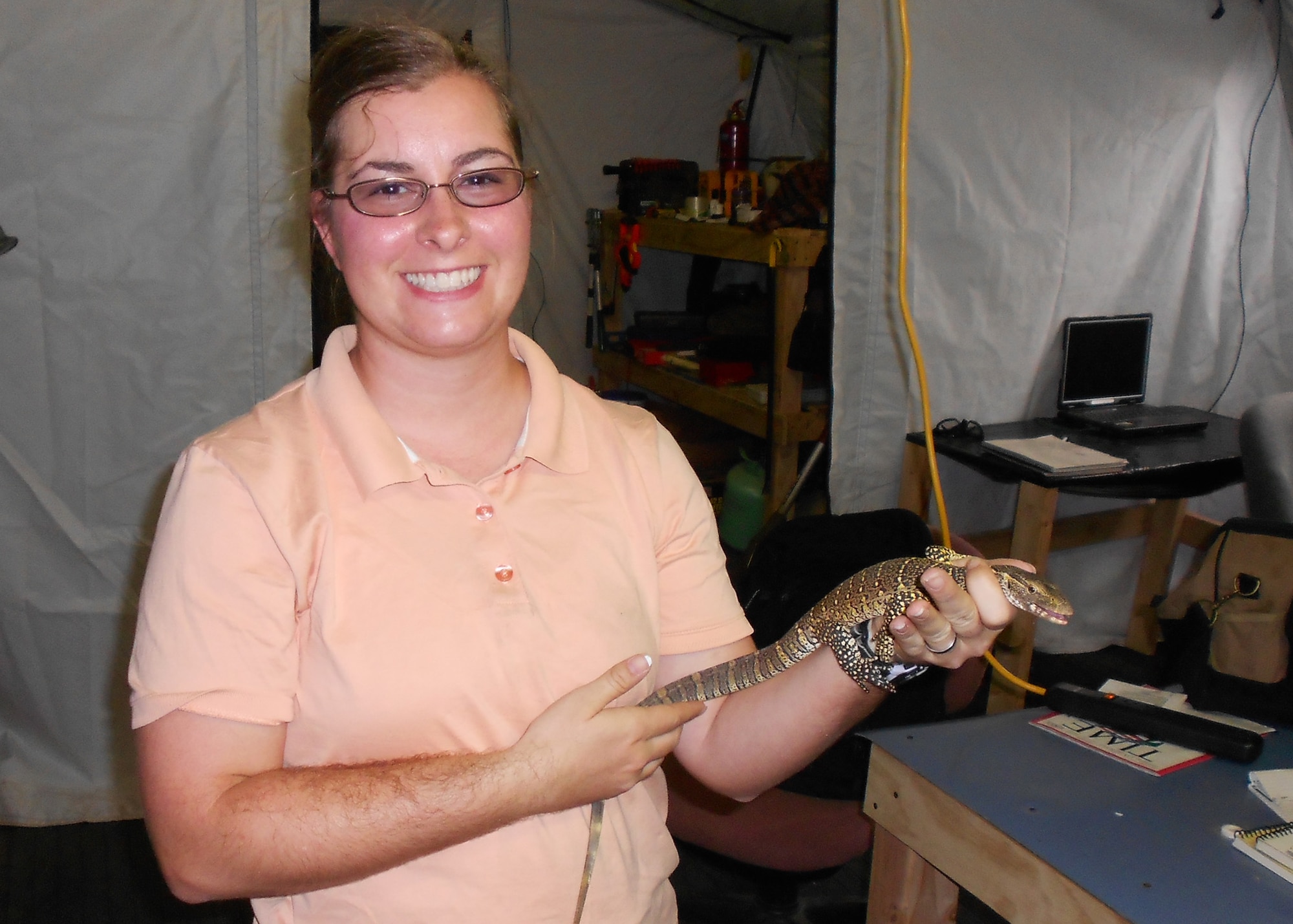Air Force Reserve Master Sgt. Jennifer Alexander displays a young monitor lizard she recently found at her deployed location.   In her duties as the deployed pest control manager for a U.S. Africa Command forward operating base, the Duke Field civil engineering Airman often works with host nation military officials to eliminate dangerous wildlife hazards and ensure non-threatening wildlife found on and near her base are safely returned to the wild. (Courtesy photo)