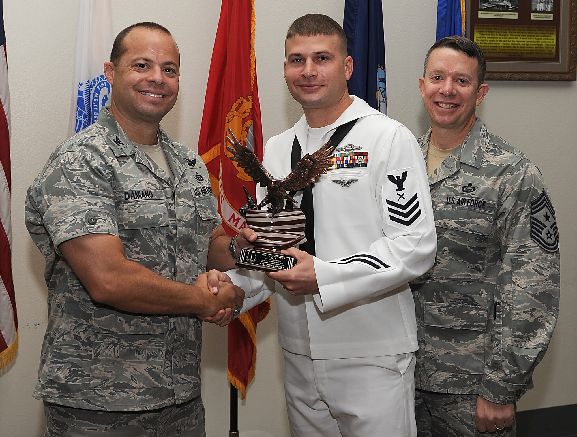 GOODFELLOW AIR FORCE BASE, Texas -- Col. Mark Damiano, 17th Training Wing Commander, and Chief Master Sgt. Brendan Criswell, 17th TRW Command Chief, present Navy Petty Officer 1st Class Joseph Oktela, U.S. Navy Center for Information Dominance Detachment, with the Team Goodfellow NCO of the Quarter Award for the third quarter.  (U.S. Air Force photo/Airman 1st Class Michael Smith)