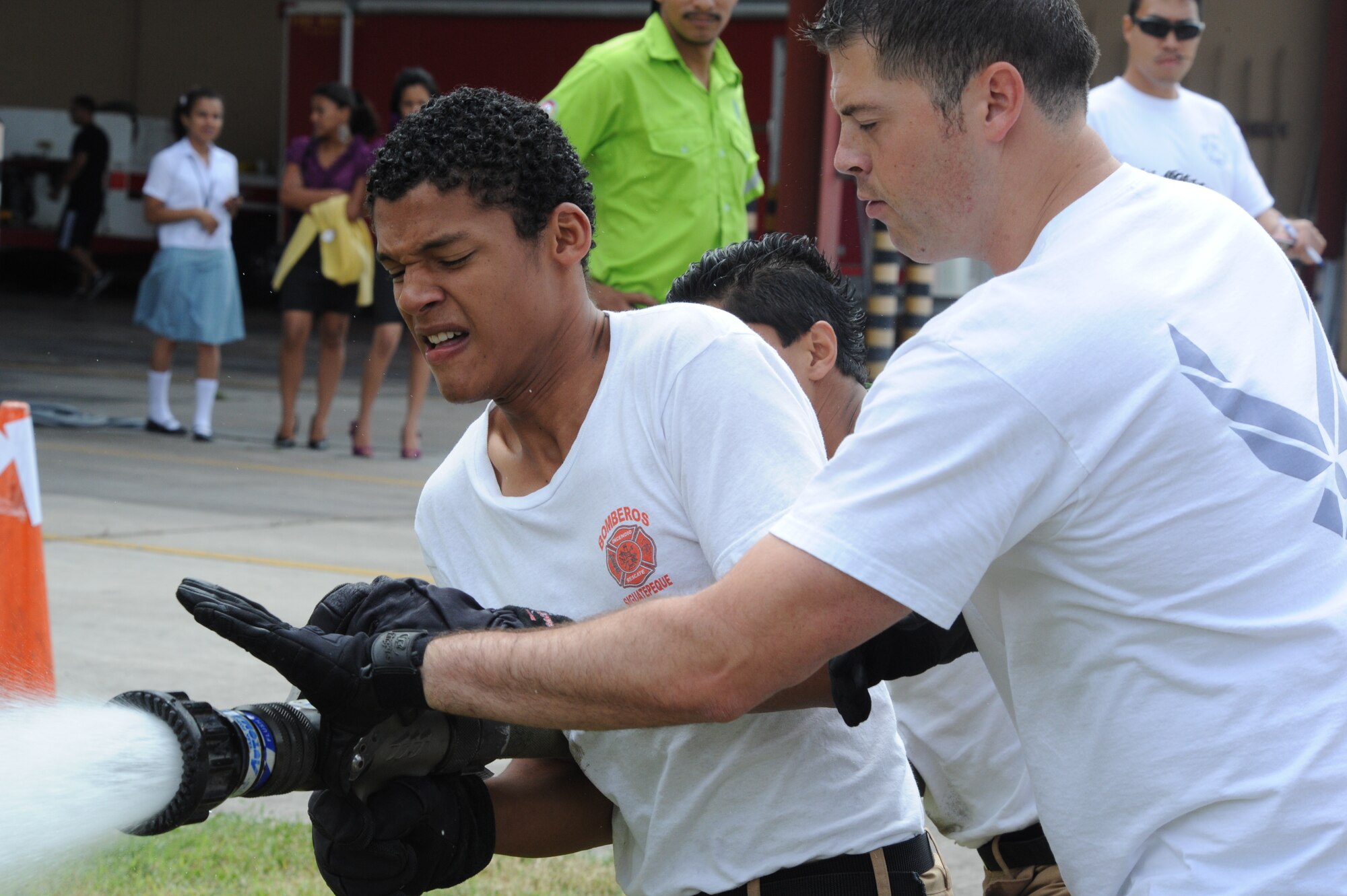 Honduran firefighters (left) receive assistance from Staff Sgt. Jack Toeller, 612th Air Base Squadron firefighter, during the hose drag portion of the Fire Muster Challenge Oct. 21, at Soto Cano Air Base, Honduras. During the muster, Honduran firefighters and Soto Cano Air Base servicemembers challenged themselves with six events simulating basic firefighting skills. (U.S. Air Force photo/Tech.Sgt. Matthew McGovern)