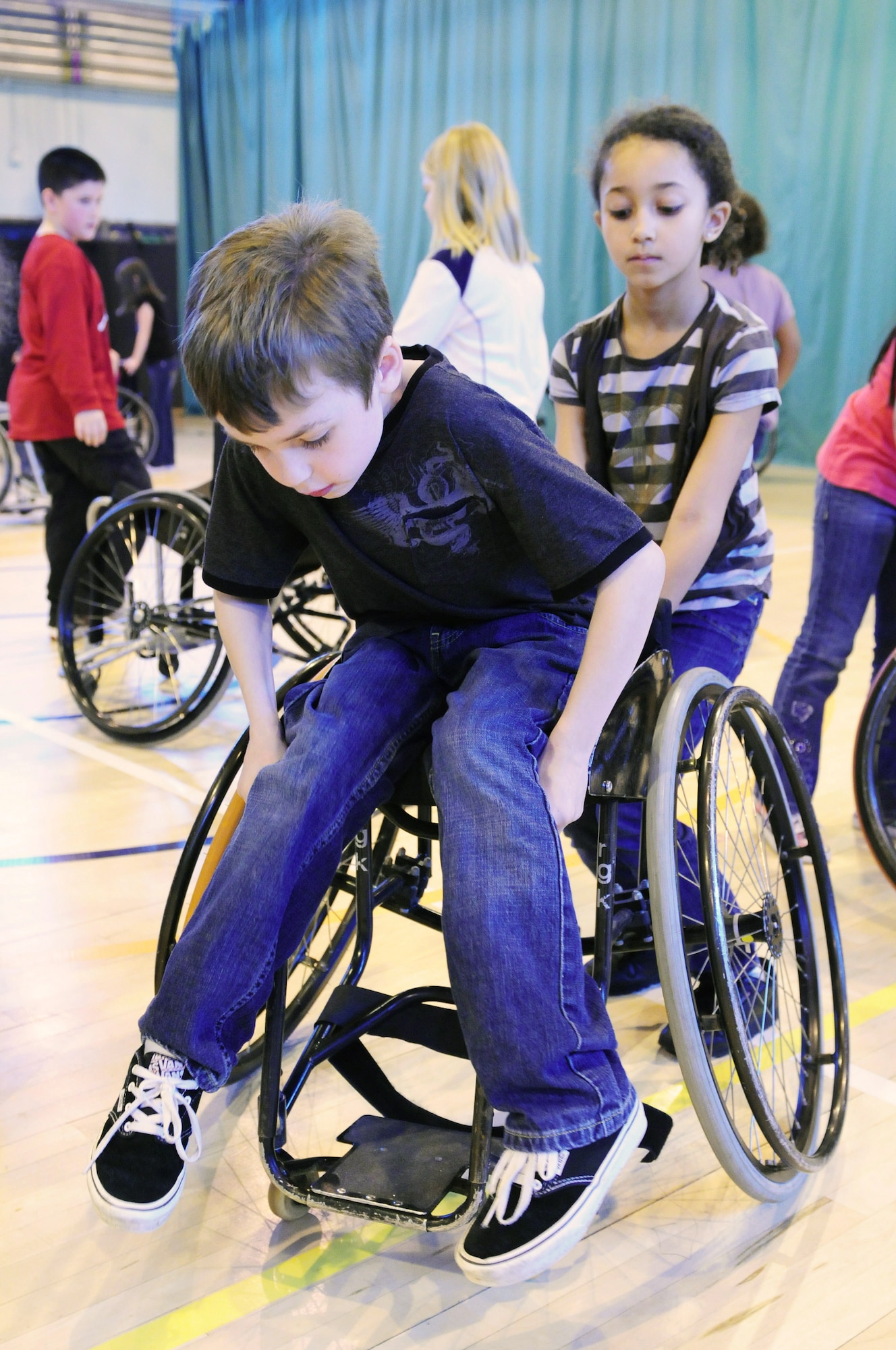 ROYAL AIR FORCE LAKENHEATH, England - Kyrah Catlin, 8, helps classmate Brennen Buchanan, 8, safely dismount from a wheelchair, Oct. 25, 2011. Sponsored by the Parent Teacher Student Organization, the Bury Bombers visited the school to perform an exhibition game for all the students for the fifth year in a row. After the game, due to the size of the wheelchairs, third grade students were given the opportunity to have a hands-on session with the players.  (U.S. Air Force photo by Senior Airman Lausanne Morgan)