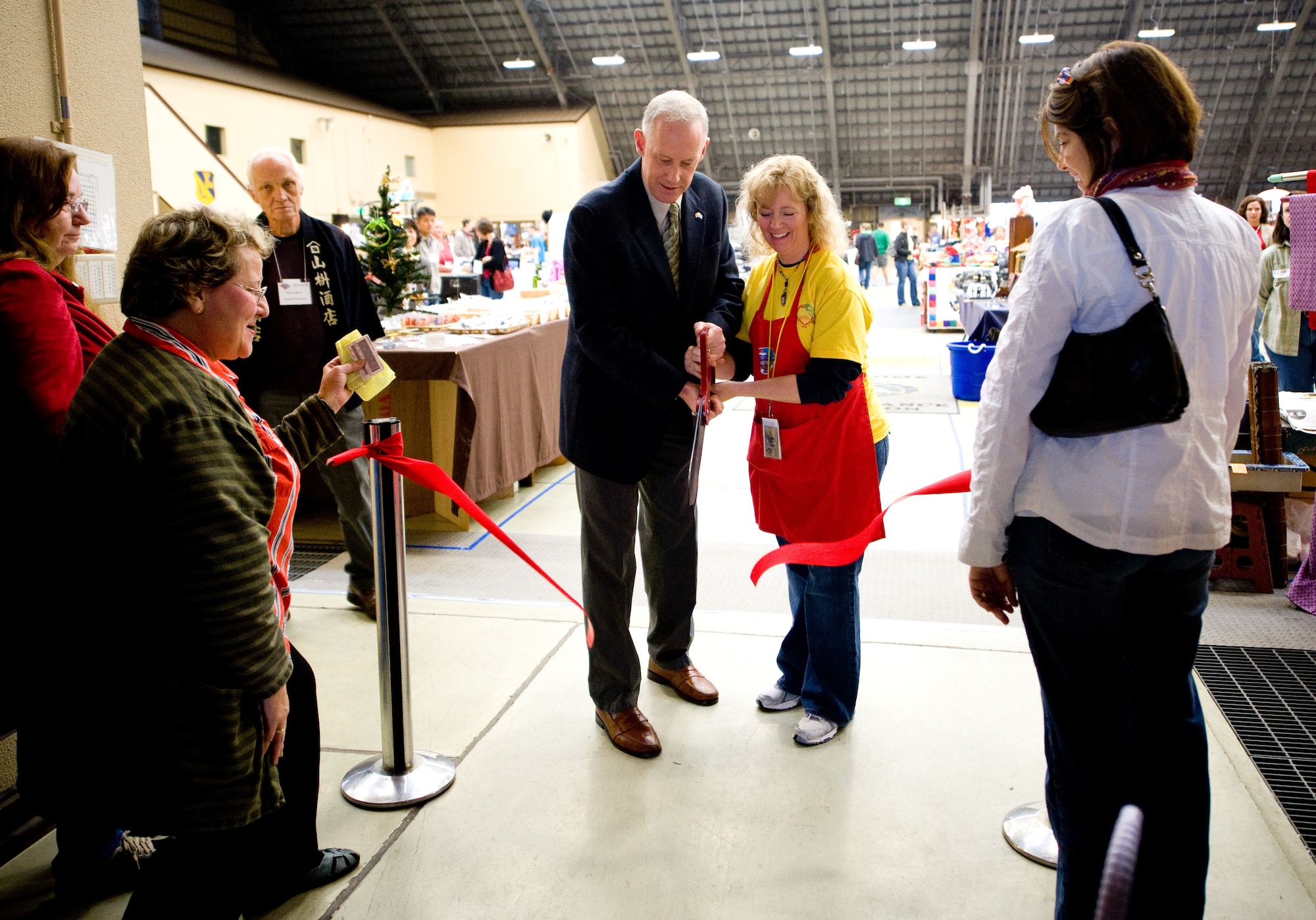 YOKOTA AIR BASE, Japan -- Col. Otto Feather, 374th Airlift Wing commander, assists Debi Reese, Yokota Officer Spouses Club Fall Bazaar chair, during the ribbon cutting ceremony signifying the start of the bazaar at Yokota Air Base, Japan, Oct. 22, 2011. More than 47 vendors from different countries participated in the event. (U.S. Air Force photo/Airman 1st Class Krystal M. Garrett) 