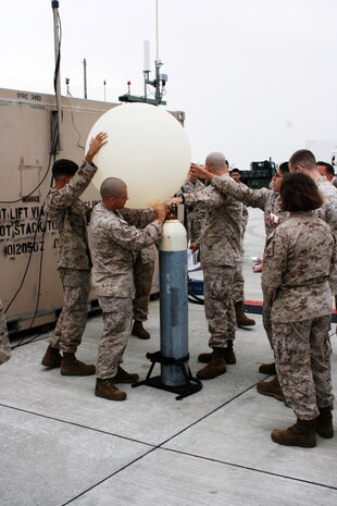 Sgt. Travis W. Patton, a meteorology oceanography analyst forecaster, holds a weather ballon while his fellow Marines help to keep it from flying away as they fill the balloon with approximatly 300 grams of Helium here Oct. 19. The weather balloon will carry up a new technology in order to help understand and forecast the upcoming weather. By being able to detect the incoming weather patterns, it allows Marines the upperhand in many situations and helps to plan attacks depending on different scenarios. The new RawinSonde-92 GPS system replaced the old RS-80 system, which has been the military’s normal system for years. Weather Marines need these Radiosonde to travel to the height of the jet stream in order to retrieve all of the most valuable intelligence. Marines still send up Radiosonde in deployed environments every day.