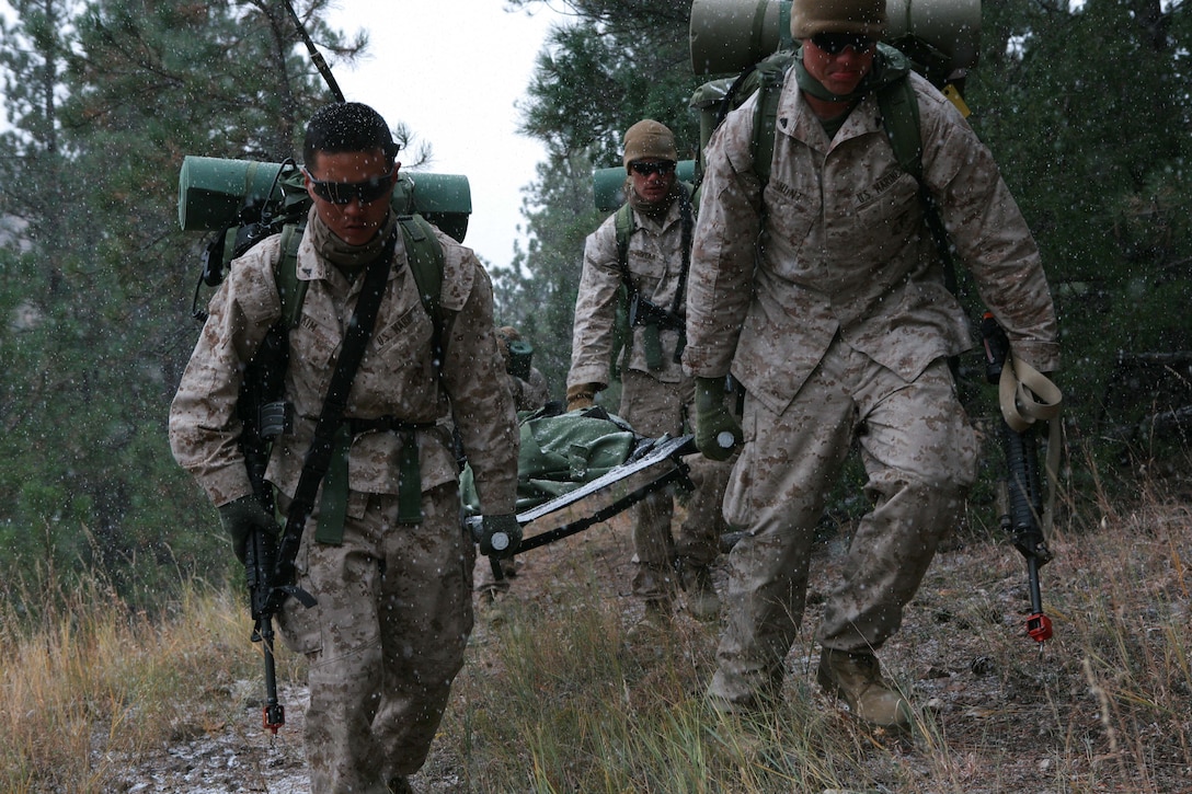 (left) Lance Cpl. Andrew D. Kim, fire support man, 2nd Air-Naval Gunfire Liaison Company, II Marine Expeditionary Force,  and other Marines with ANGLICO, carry a 250-pound stretcher up the side of a hill for a mock medical evacuation aboard Camp Guernsey Army Air Field, Wyo., Oct. 27. The exercise was part of a two-day event covering numerous skills such as patrolling and air strikes. Over the two-day event ANGLICO conducted approximately 20 different exercises to prepare for an upcoming deployment to Afghanistan.