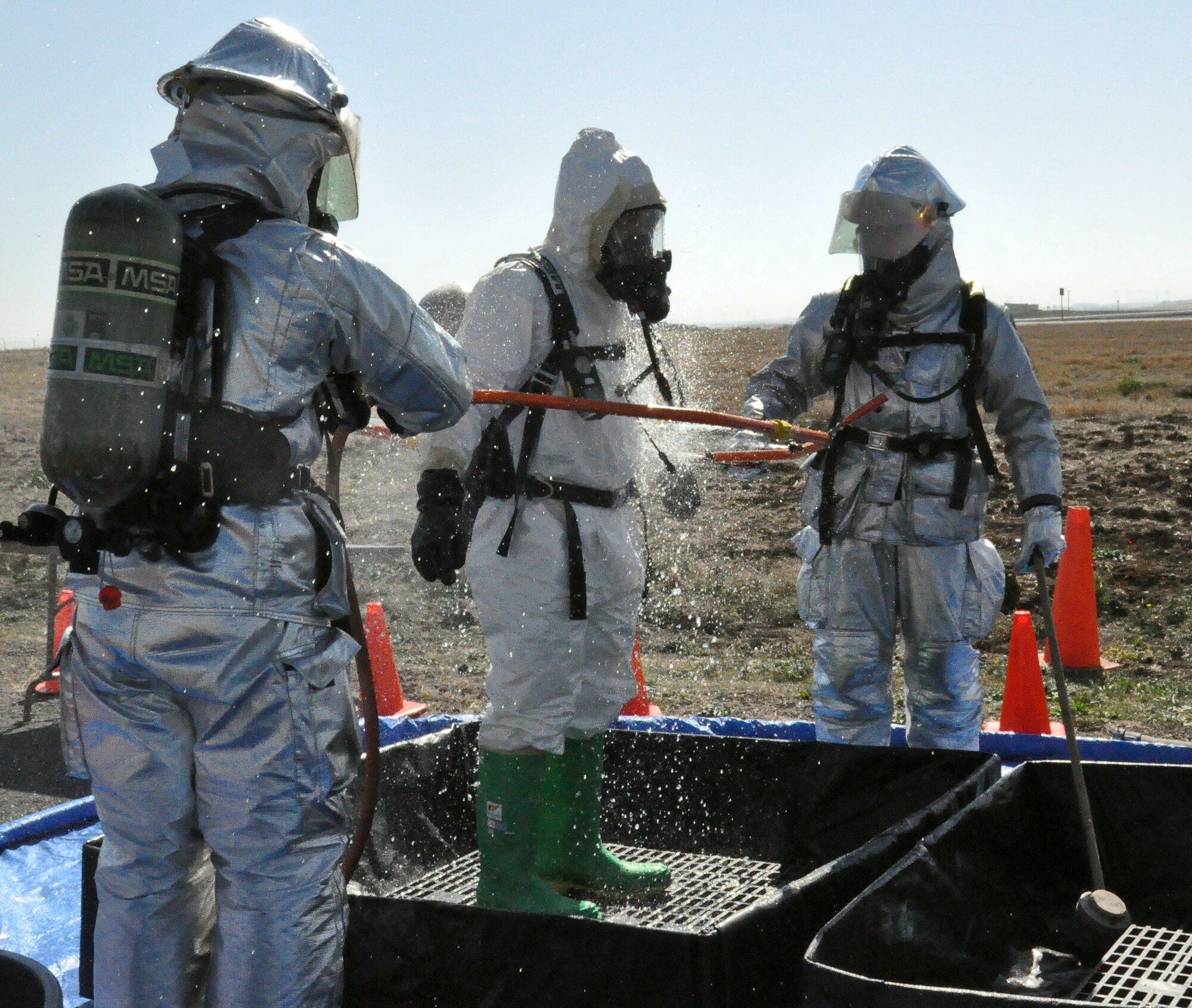 Members of fire and emergency begin the decontamination process for Staff Sgt. Ronald Cruz, 60th Medical Group, during an exercise after he came in contact with hazardous material Oct. 20 during the scenario. (U.S. Air Force photo/ Airman Madelyn Ottem)