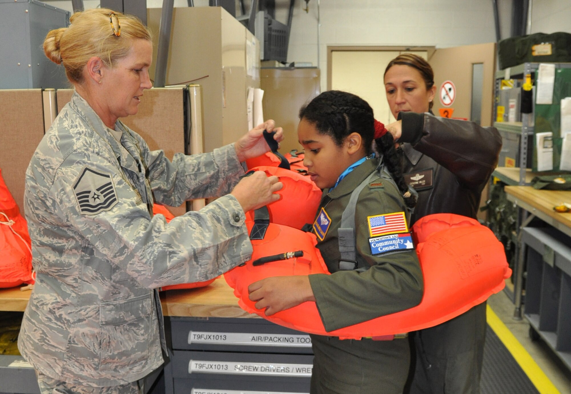 YOUNGSTOWN AIR RESERVE STATION, Ohio — Air Force Reserve Master Sgt. Cindy Cox, a life support equipment craftsman with the 910th Airlift Wing and Lt. Col. Cathy Miller, a C-130 pilot with the 910th help 10-year-old Rosalinda "Rosie" Shakari of Campbell, Ohio don a life vest here October 26.  Rosie was selected by Akron Children's Hospital Mahoning Valley to be honored as a pilot for a day. She is being treated for chronic asthma. Rosie was sworn in as an honorary second lieutenant, taxied aboard a C-130 Hercules aircraft and given a special tour of the installation. The pilot for a day program began in 2000 to help bring a ray of sunshine into the lives of children being treated for chronic or life threatening conditions. U.S. Air Force photo by Maj. Brent J. Davis