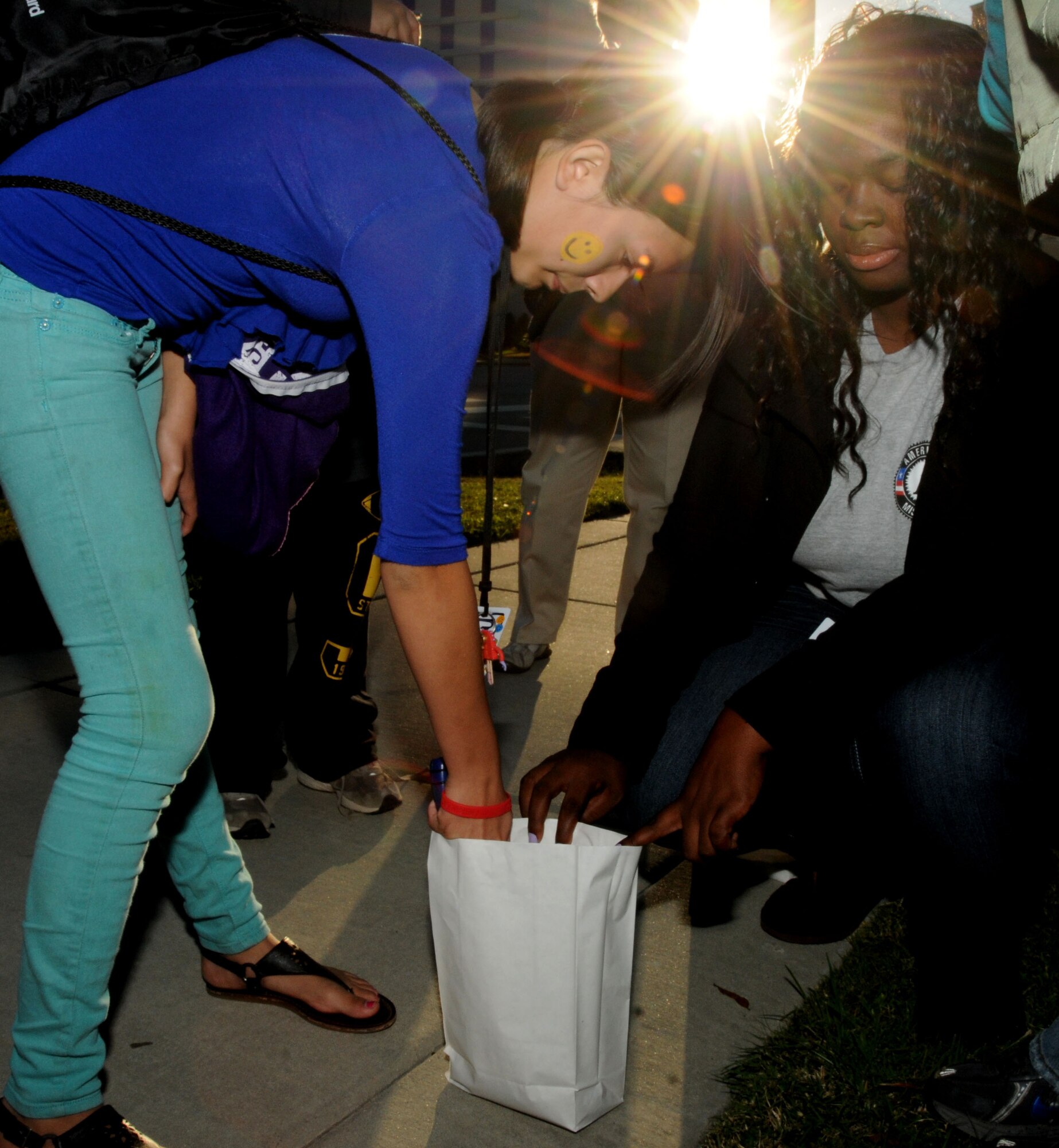 Twelve-year-old Samaya Holcomb receives help from Latrice Bruce, Americorps Boys and Girls Club member from East Biloxi, with lighting one of the luminaries lined up along the sidewalk on U.S. Highway 90 during the "Lights on After School" celebration at Biloxi Town Green Oct. 20, 2011.  Samaya, who attends Keesler 's youth center after-school open recreation program, is the daughter of Tech Sgts. Claudia Holcomb, 81st Dental Squadron, and Jeremy Holcomb, 85th Engineering Installation Squadron, Keesler Air Force Base, Miss.  (U.S. Air Force photo by Kemberly Groue)