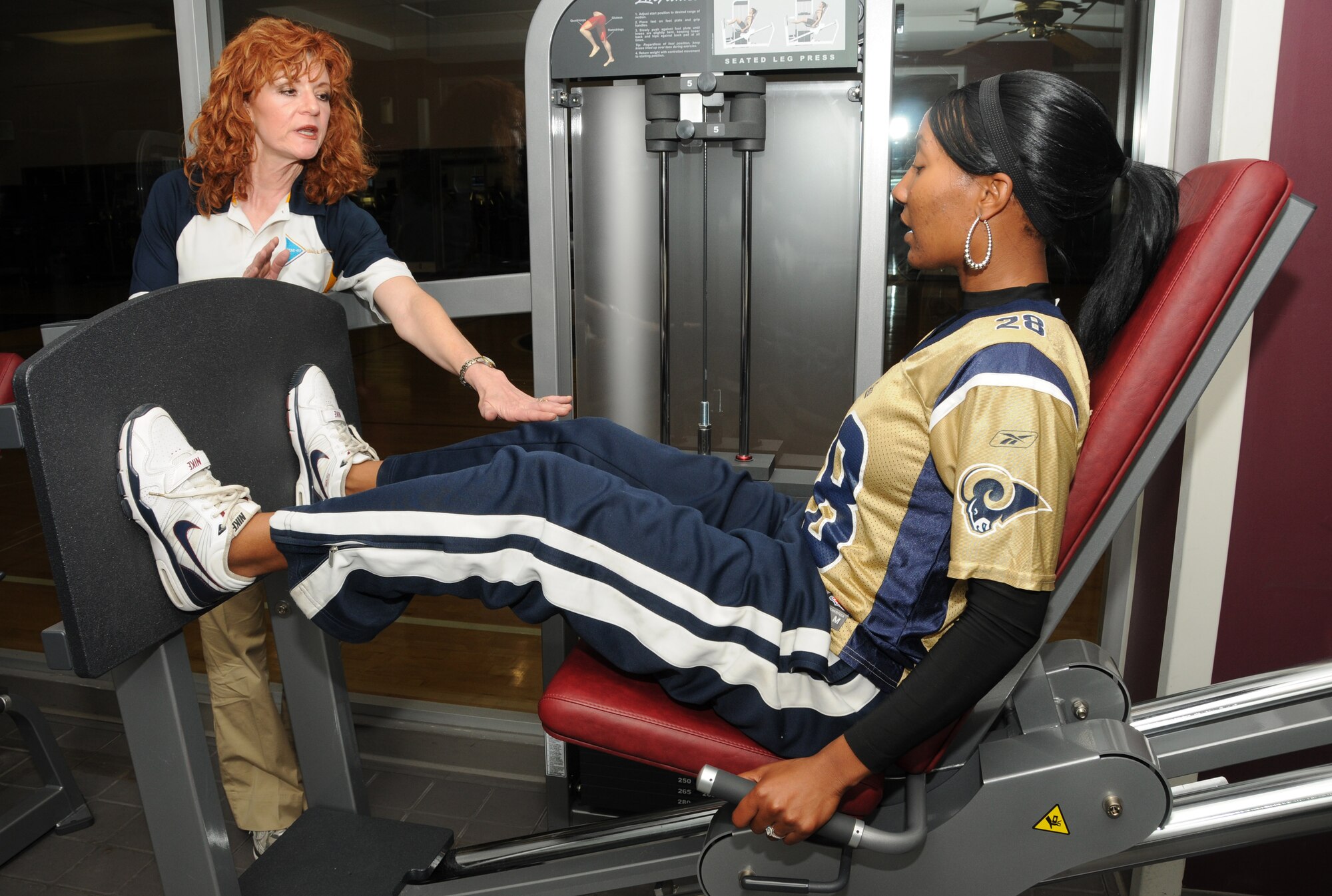 Left, Donna Flynn, a fitness center trainer, assists Tech Sgt. Tomeika Washington, 81st Force Support Squadron, with using the seated leg press strengthening equipment at the Dragon Fitness Center Oct. 20, 2011, Keesler Air Force Base, Miss. The primary goal of Keesler’s fitness services is to assist all customers in improving their overall fitness level and quality of life.  (U.S. Air Force photo by Kemberly Groue)