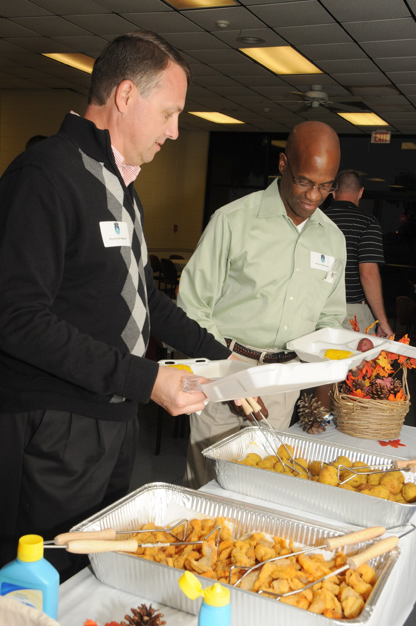 Left, Brig. Gen. Earl Matthews, Director, Cyberspace Operations, Office of Information Dominance and Chief Information Officer, Office of the Secretary of the Air Force, the Pentagon, Washington D.C. and Maj. Gen. Edward Bolton Jr., Director, Space and Cyber Operations, Deputy Chief of Staff for Operations, Plans and Requirements, Headquarters U.S. Air Force, Washington, D.C., enjoy  the fish fry buffet set up inside the indoor pavilion at marina park during Scope Warrior.  The fish fry is sponsored by the Biloxi Chamber of Commerce.  Scope Warrior was held at Keesler Air Force Base, Miss., Oct. 17-21, 2011. Scope Warrior is an annual event for Air Force senior communications leaders.  (U.S. Air Force photo by Kemberly Groue)