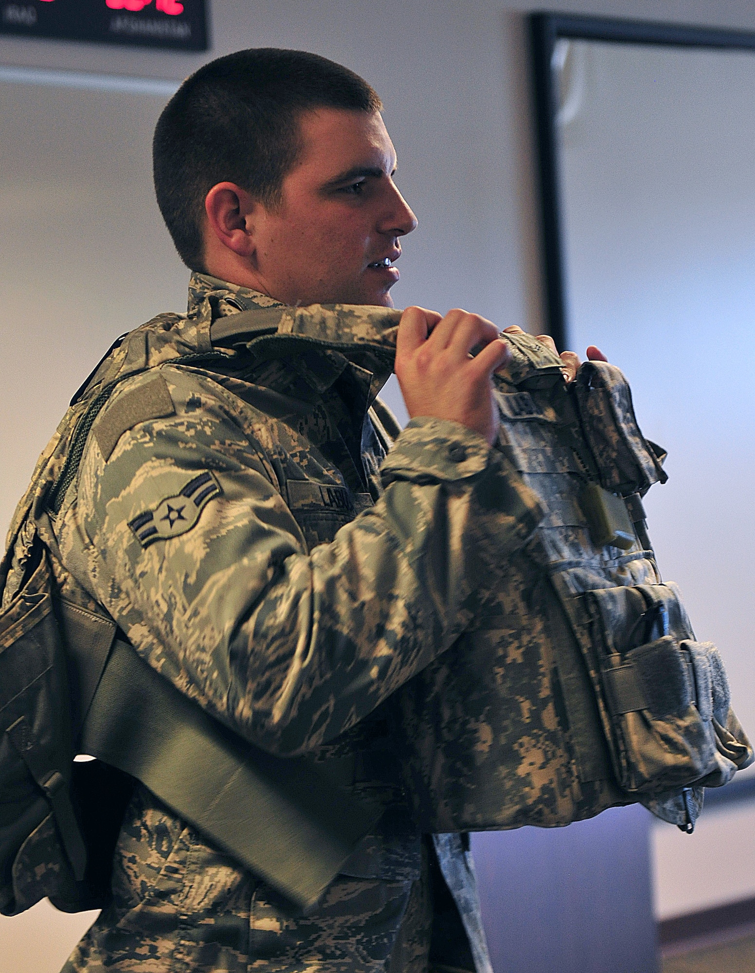 U.S. Air Force Airman 1st Class Christopher Labuda, 823rd Base Defense Squadron fire team member, removes his interceptor body armor at the Deployment Control Center at Moody Air Force Base, Ga., Oct. 23, 2011. The DCC is the final processing location the members went before their flight to Camp Smith, N.Y., for a 10-day training mission. (U.S. Air Force photo by Senior Airman Stephanie Mancha/Released)