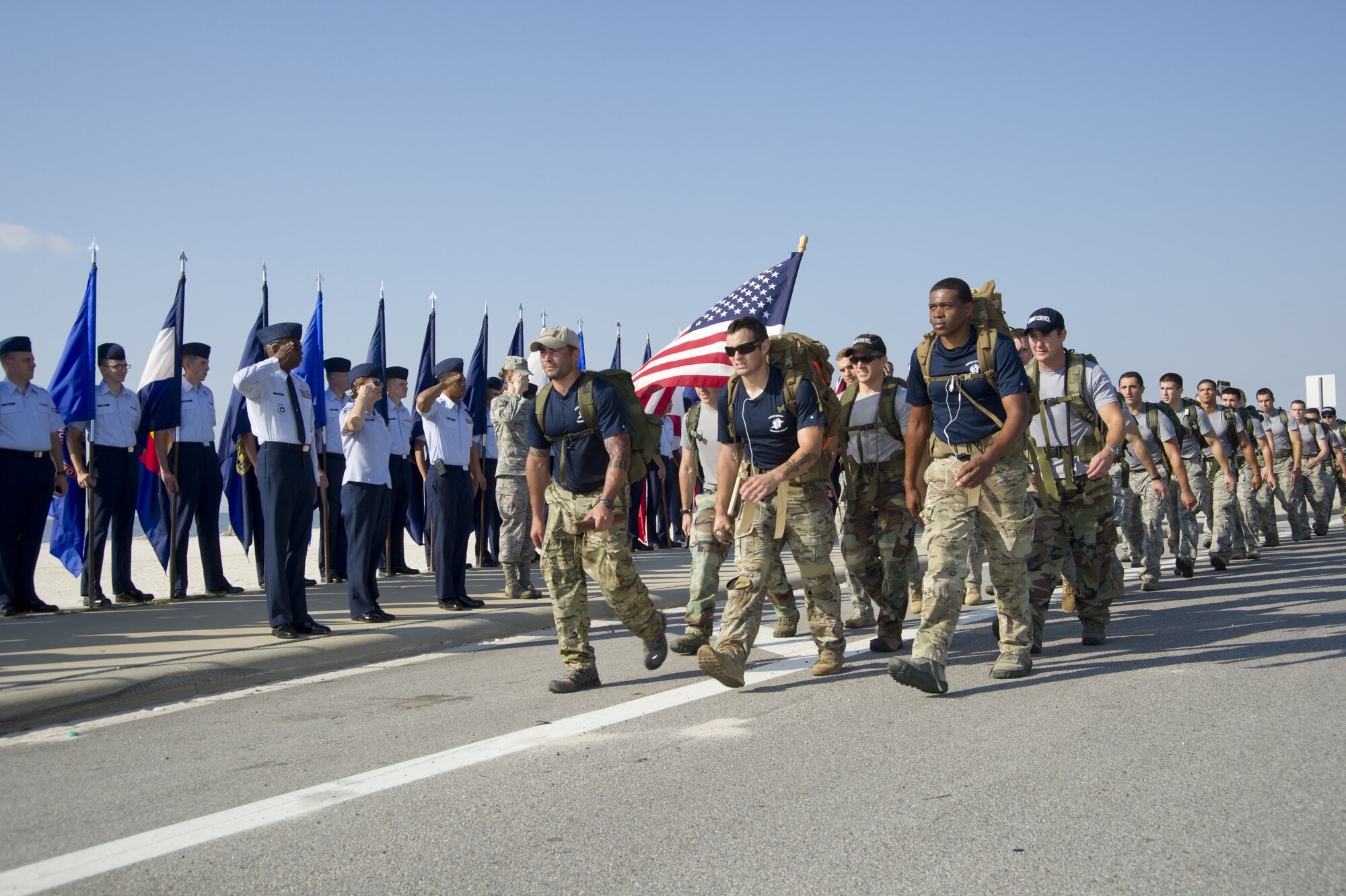 Members of the 812-mile Tim Davis Memorial March pass by Keesler Air Force Base, Miss., as they make their way along U.S. Highway 90 in Biloxi Oct. 24, 2011. The march honors special tactics Airmen who have died fighting in Iraq and Afghanistan. In the background, Keesler Airmen salute the flag while nearly 40 combat control instructors and trainees from the 334th Training Squadron joined the march as it neared Keesler and other Airmen lined the highway to salute the flag. The march began at Lackland Air Force Base, Texas, Oct. 16 and ended at the Special Tactics Training Squadron at Hurlburt Field, Fla., Oct. 26.  (U.S. Air Force photo by Adam Bond)