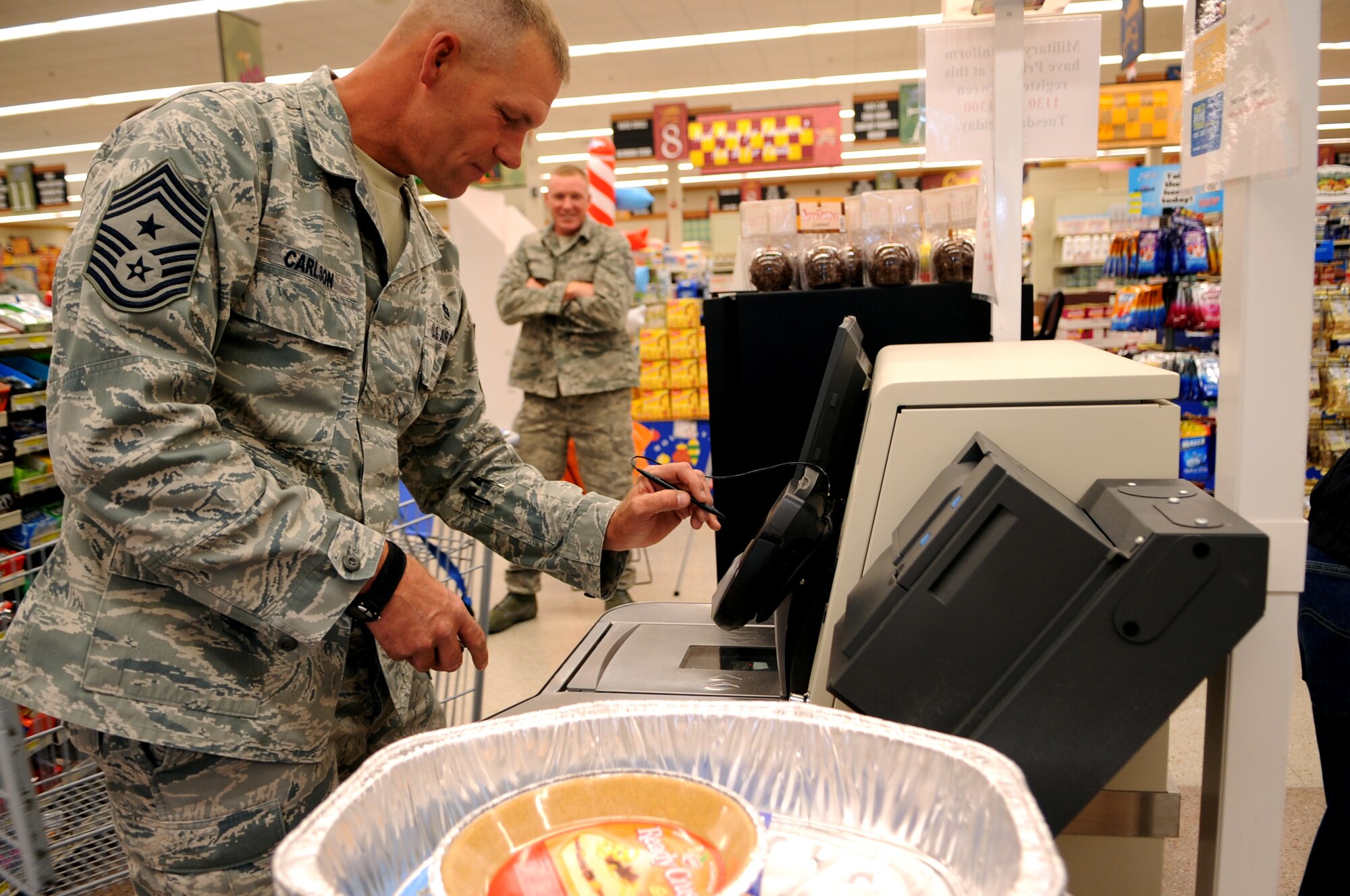 Command Chief Master Sgt. Dave Carlson, 319th Air Base Wing, pays for the food items to donate to Operation Warmheart at Grand Forks Air Force Base, N.D., on Oct. 25. Operation Warmheart is a community outreach program of the GFAFB First Sergeant Council that collects donations to provide a no-cost Thanksgiving dinner for Airmen on base. Donations are being accepted at the base commissary. (U.S. Air Force photo by Senior Airman Amanda N. Stencil)