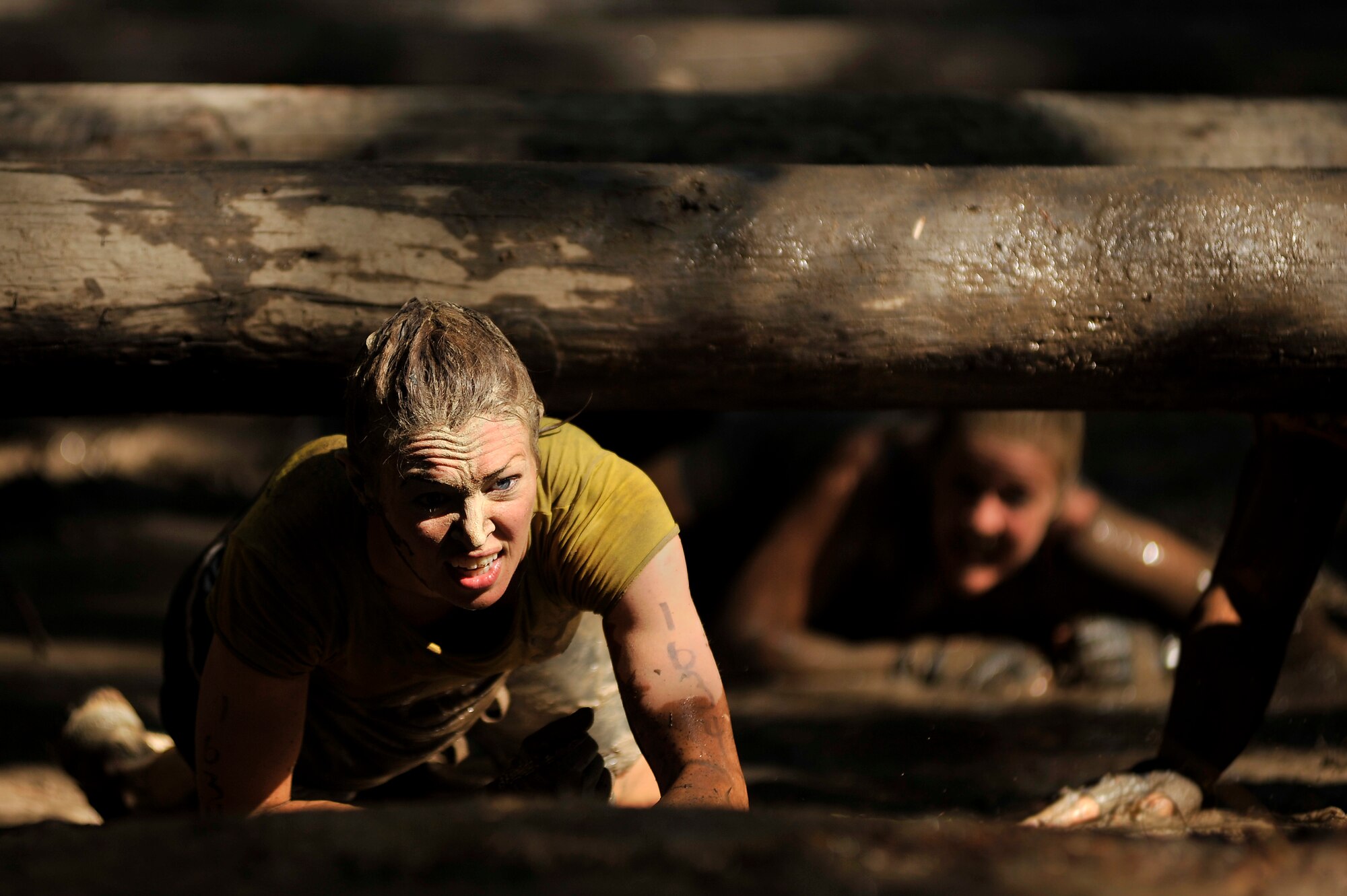 A participant of the U.S. Marine Corps Mud Run low crawls under several suspended logs as she leads her team to the next check point of the race, Oct. 15, 2011, Columbia, S.C. Participants competed in four person teams in different categories: male, female, co-ed, homeland heroes, military, corporate and JROTC. (U.S. Air Force photo by Senior Airman Kenny Holston/Released)


