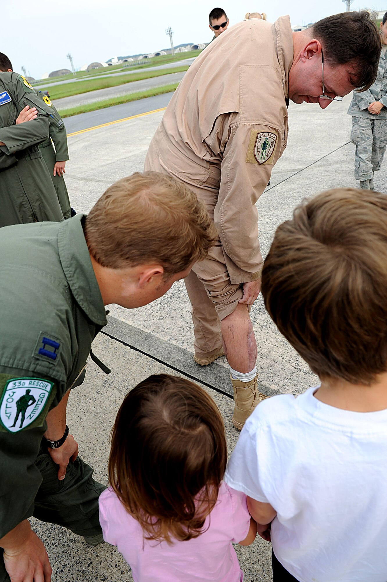 U.S. Air Force Tech. Sgt. James Davis, 33rd Rescue Squadron flight engineer, shows off his scars from the gunshot wound he received while serving over in Afghanistan this spring to his children and co-workers on Kadena Air Base, Japan, Oct. 26. Davis is returning home to Kadena from Travis Air Force Base, Calif. after spending several months in rehabilitation for a gunshot wound he acquired while serving in Afghanistan this spring. (U.S. Air Force photo/Airman 1st Class Brooke P. Beers/Released)