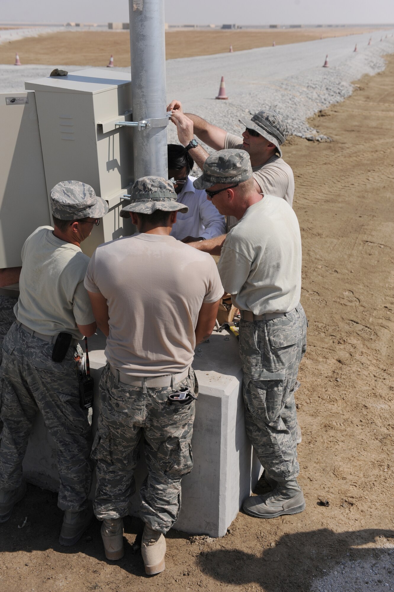 A group of 380th Expeditionary Civil Engineer Squadron members installs a solar light in the munitions storage area of the 380th Air Expeditionary Wing Oct. 17, 2011. The engineers will install 24 energy efficient solar lights that will provide fossil fuel savings while also enabling fixed lighting in an area of the base that is not connected to the energy grid.  (U.S. Air Force photo/Master Sgt. Chance Babin)