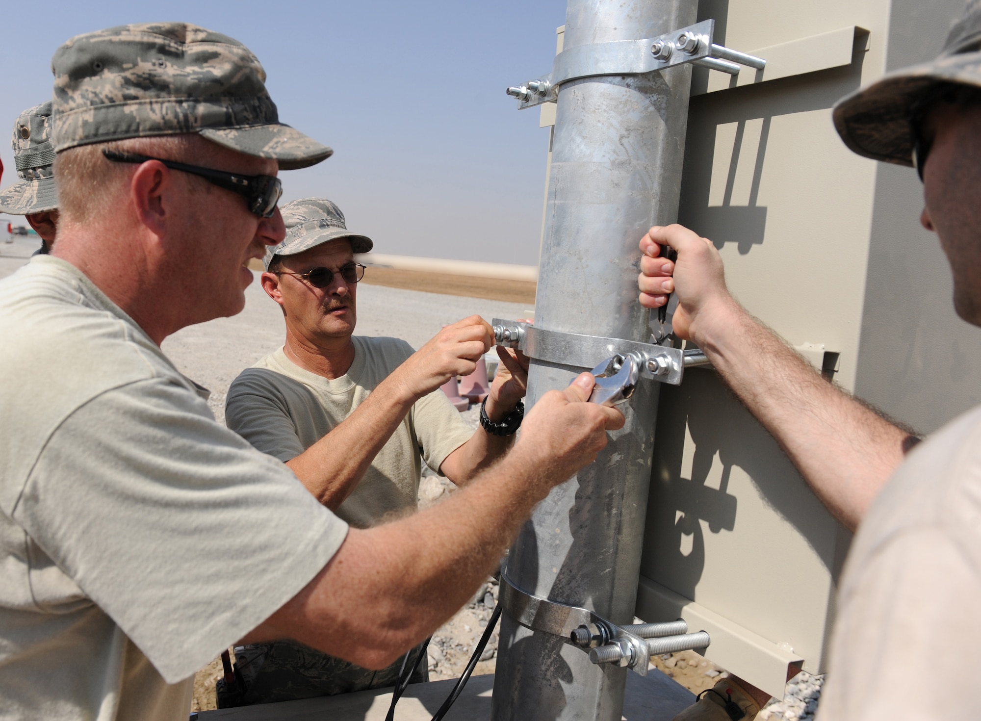 Master Sgt. Joseph Moss and Tech. Sgt. Jeffrey Welte install bolts on the solar light control box at the munitions storage area at the 380th Air Expeditionary Wing Oct. 17, 2011. The engineers will install 24 energy efficient solar lights that will provide fossil fuel savings while also enabling fixed lighting in an area of the base that is not connected to the energy grid. (U.S. Air Force photo/Master Sgt. Chance Babin)