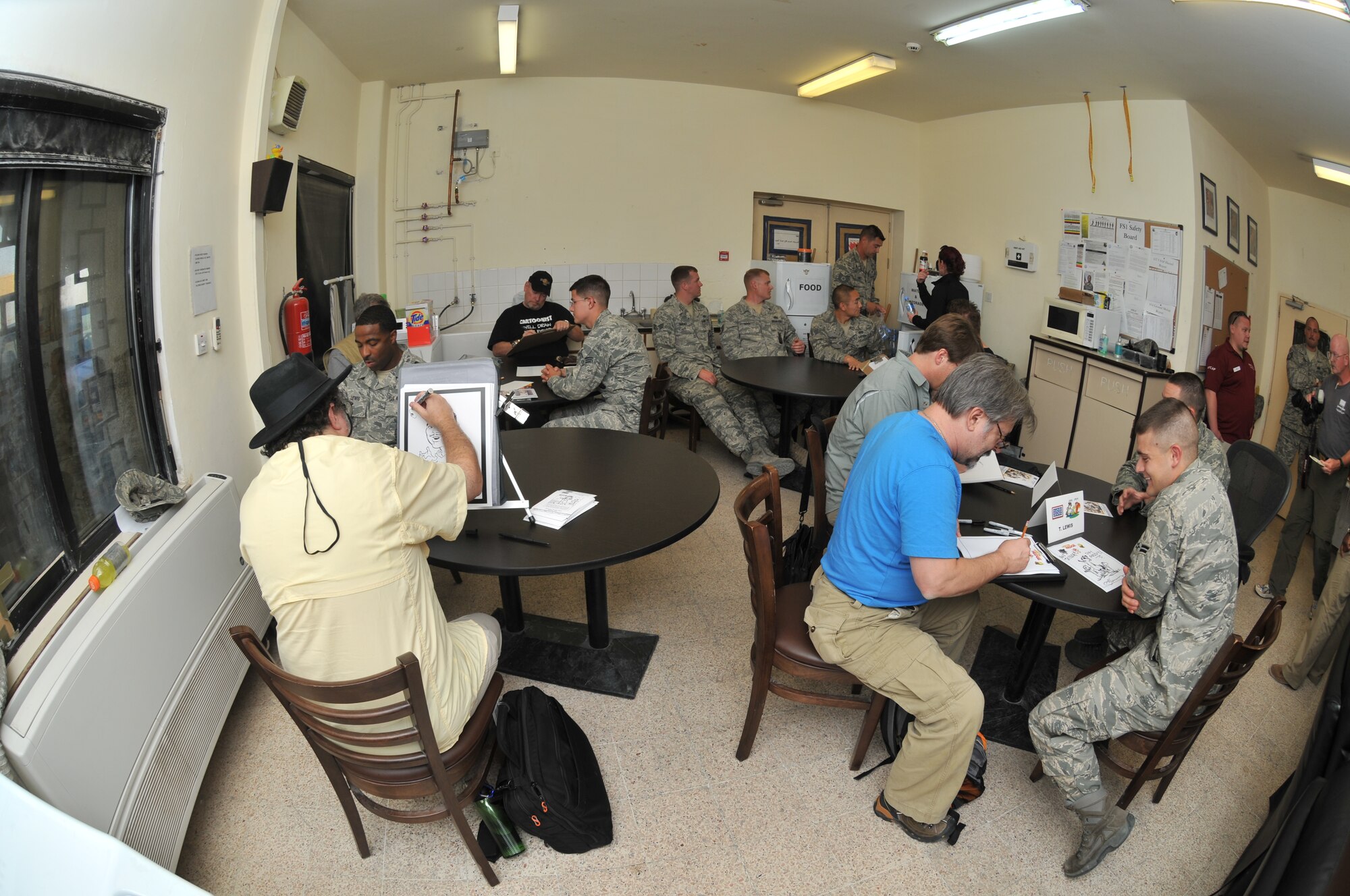 Airmen from the 379th Expeditionary Civil Engineer Squadron fire department have caricatures drawn by several artists during a USO-sponsored tour by National Cartoonists Society members Oct. 22, 2011, at an undisclosed location in Southwest Asia. The cartoonists visited several  areas on base and drew pictures of servicemembers to help boost morale. (U.S. Air Force photo/Senior Airman Eric Summers Jr.)