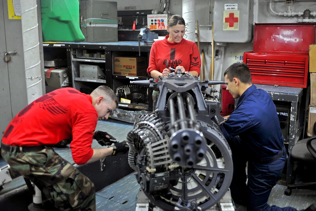 U.S. Navy Petty Officer 2nd Class Kimberly Rogers, center, supervises Seamen Aaron Deskins, left, and Tyler Tassio, as they work on an M-61A2 Vulcan 20-mm Gatling gun in the aviation ordnance shop aboard the aircraft carrier USS George Washington in the Pacific Ocean, Oct. 25, 2011. Rogers is an aviation ordnanceman, Deskins is an airman and  Tassio is an aviation ordnanceman airman. The George Washington is currently conducting a patrol while deployed to the western Pacific region.