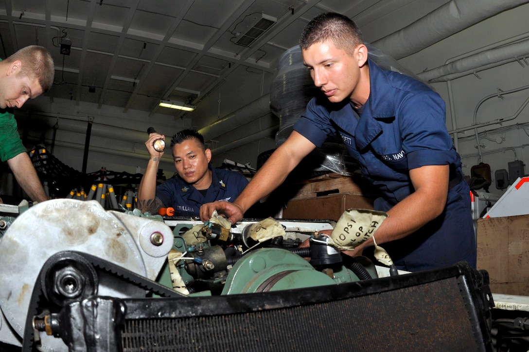 U.S. Navy Seaman Forrest Hargett installs an engine on an aircraft tug in the hangar bay of the aircraft carrier USS Ronald Reagan in the Pacific Ocean, Oct. 22, 2011. Hargett is an aviation support equipment technician airman.