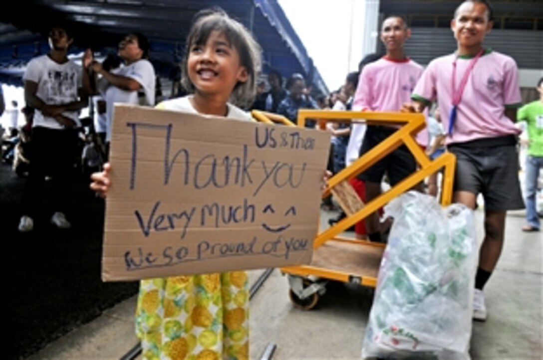 A child from the local community holds a sign thanking the U.S. sailors from the guided missile destroyer USS Mustin and members of the Thai armed forces during a community service event organized by the Princess Pa Foundation, Thai Red Cross Society, in Utapao, Thailand Oct. 23, 2011.