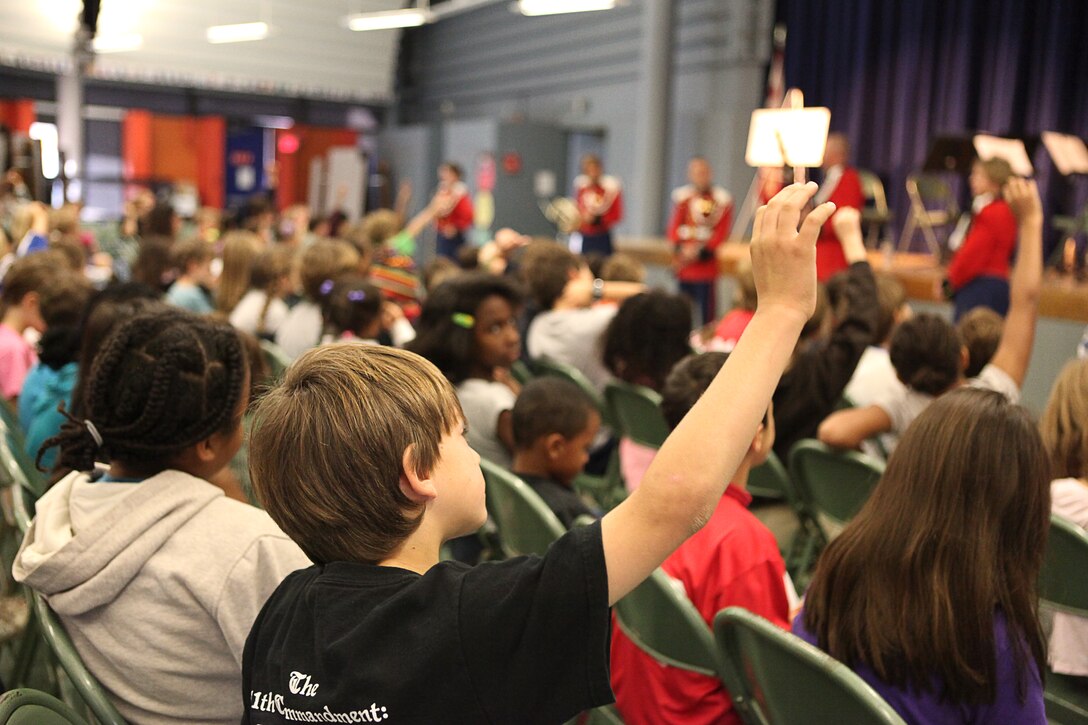 Students raise their hands to ask members of the U.S. Marine Band questions during a Music in the Schools presentation at Lafayette Elementary School here Oct. 26. For approximately five decades, the MITS program and “The President’s Own” musicians have brought education and entertainment to children through small instrumental group performances. The U.S Marine Band conducted more than 30 performances in D.C. area primary schools bringing music to approximately 5,000 students throughout the month of October.