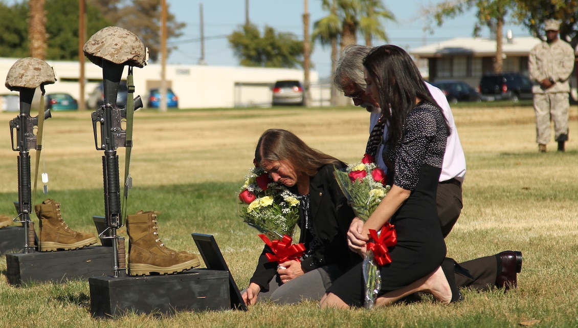 Mannette Zanowick, mother of Cpl. Paul W. Zanowick II, grieves in front of her son's battlefield cross alongside his father, Paul, and wife, Ryanlynn, during the 3rd Battalion, 4th Marine Regiment's memorial service held at Lance Cpl. Torrey L. Gray Field Oct. 27, 2011. The unit lost five Marines during their deployment.