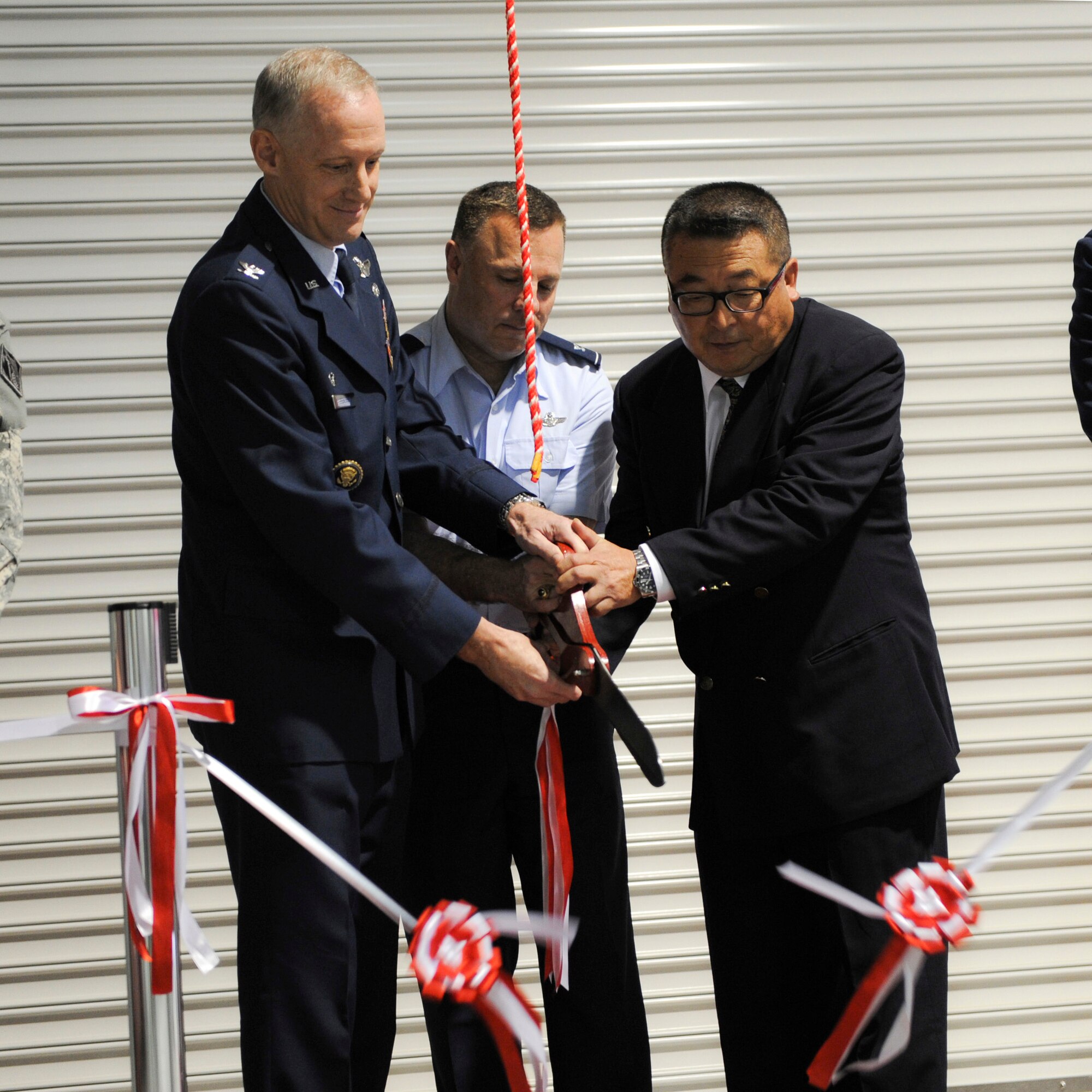 YOKOTA AIR BASE, Japan -- Col. Otto Feather, 374th Airlift Wing commander, Col. Robert Ricci, 515th Air Mobility Operations Group commander, and Mr. Norio cut the ribbon for the official opening of the new Western Pacific Transportation Facility here Oct. 24, 2011, the facility will serve a number of functions. It will be used as the Air Mobility Command Aerial Port, Pacific Air Forces Mail Terminal and the Defense Courier Division Station Operations Center. It will also be utilized by the Japan Air Self Defense Force and the Navy Air Clearance Authority.(U.S. Air Force Photo/ Staff Sgt. Stacy Moless)