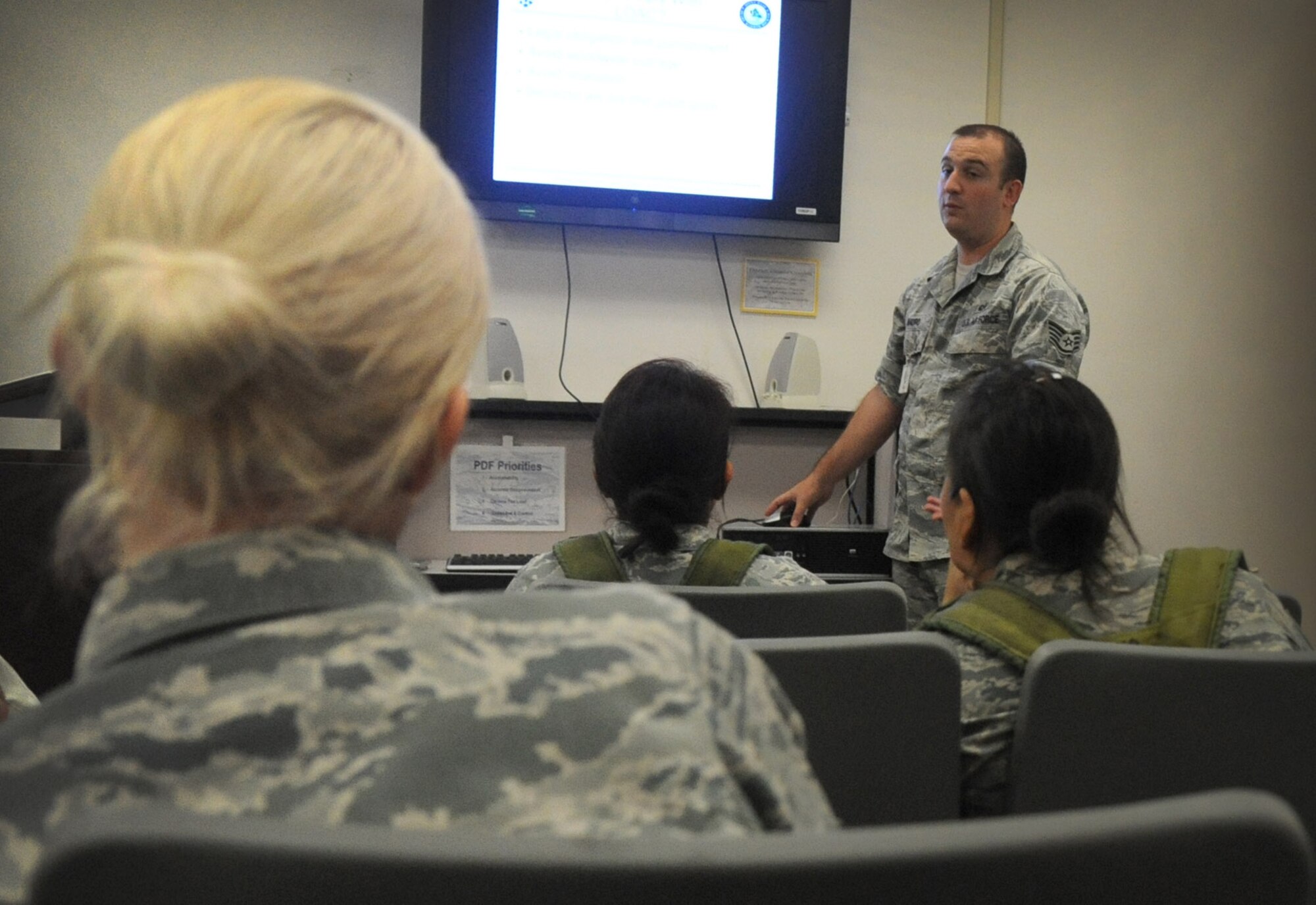 Staff Sgt, Robert Mauro, military justice paralegal with the 15th Wing Legal Office, delivers a brief to role-playing Airmen who are simulating a mass out-processing brief for an Operational Readiness Exercise on Joint Base Pearl Harbor-Hickam, Hawaii, Oct. 27. Various agencies brief Airmen prior to a deployment to ensure that Airmen and families know what to expect and what they are entitled to during their deployment and period of separation. (U.S. Air Force photo/Senior Airman Lauren Main)