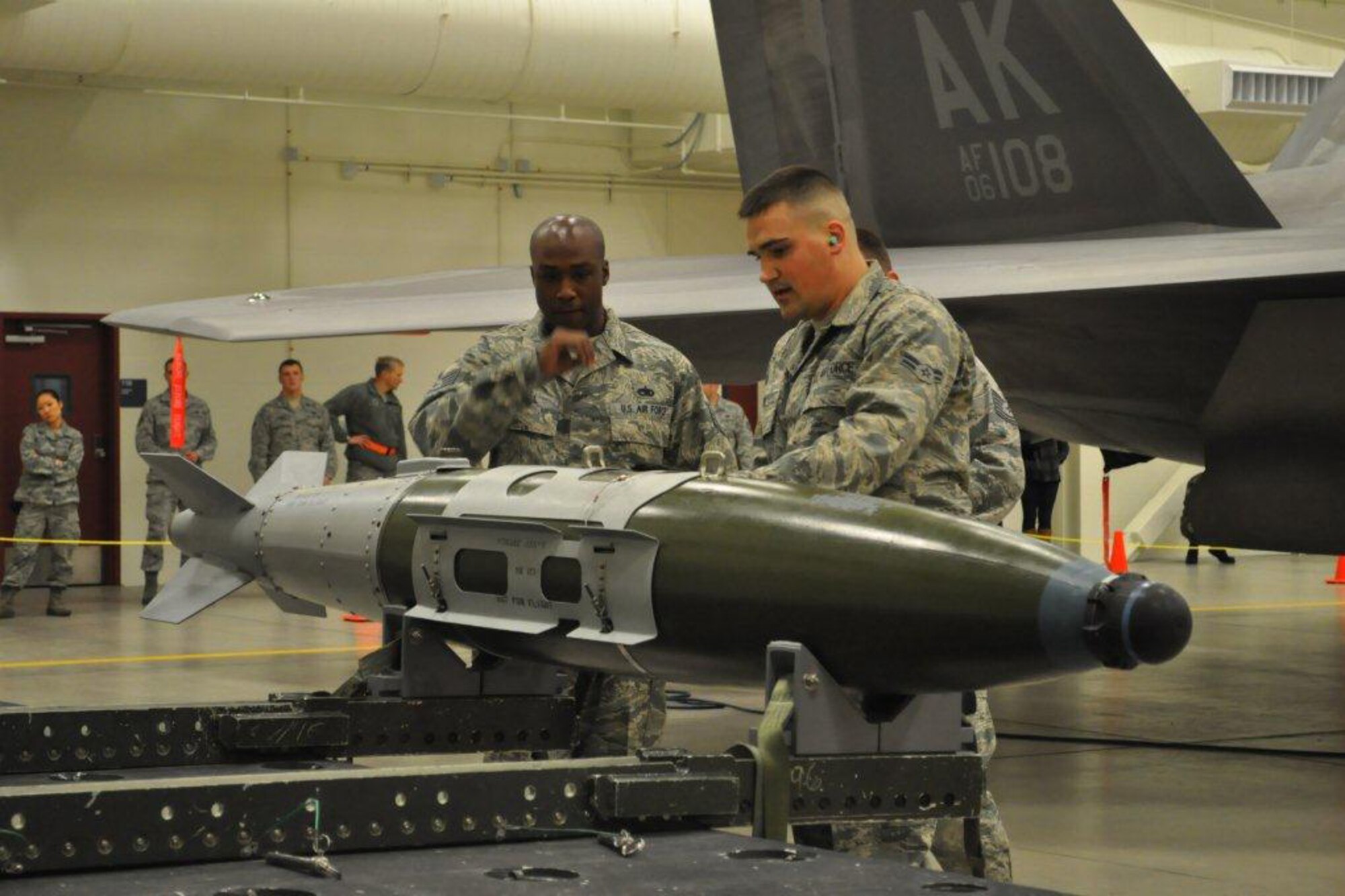 Tech Sgt. Kimmie Samuel, center, Airman 1st Class Caleb Hill, right and Airman 1st Class Wesley Beversdorf, all of the 90th Aircraft Maintenance Unit inspect a Joint Direct Attack Munition at Fighter Town Oct. 21 during the 3rd Wing quarterly weapons load competition. (Courtesy photo)