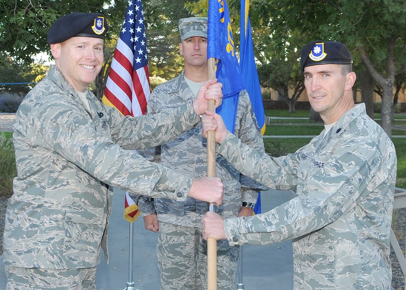 Lt. Col. Earl Layne, 377th Security Forces Group commander, left, passes the guidon Oct. 21 to Lt. Col. Bryan Eckart, 377th Weapons Systems Security Squadron commander, during a change of command ceremony.