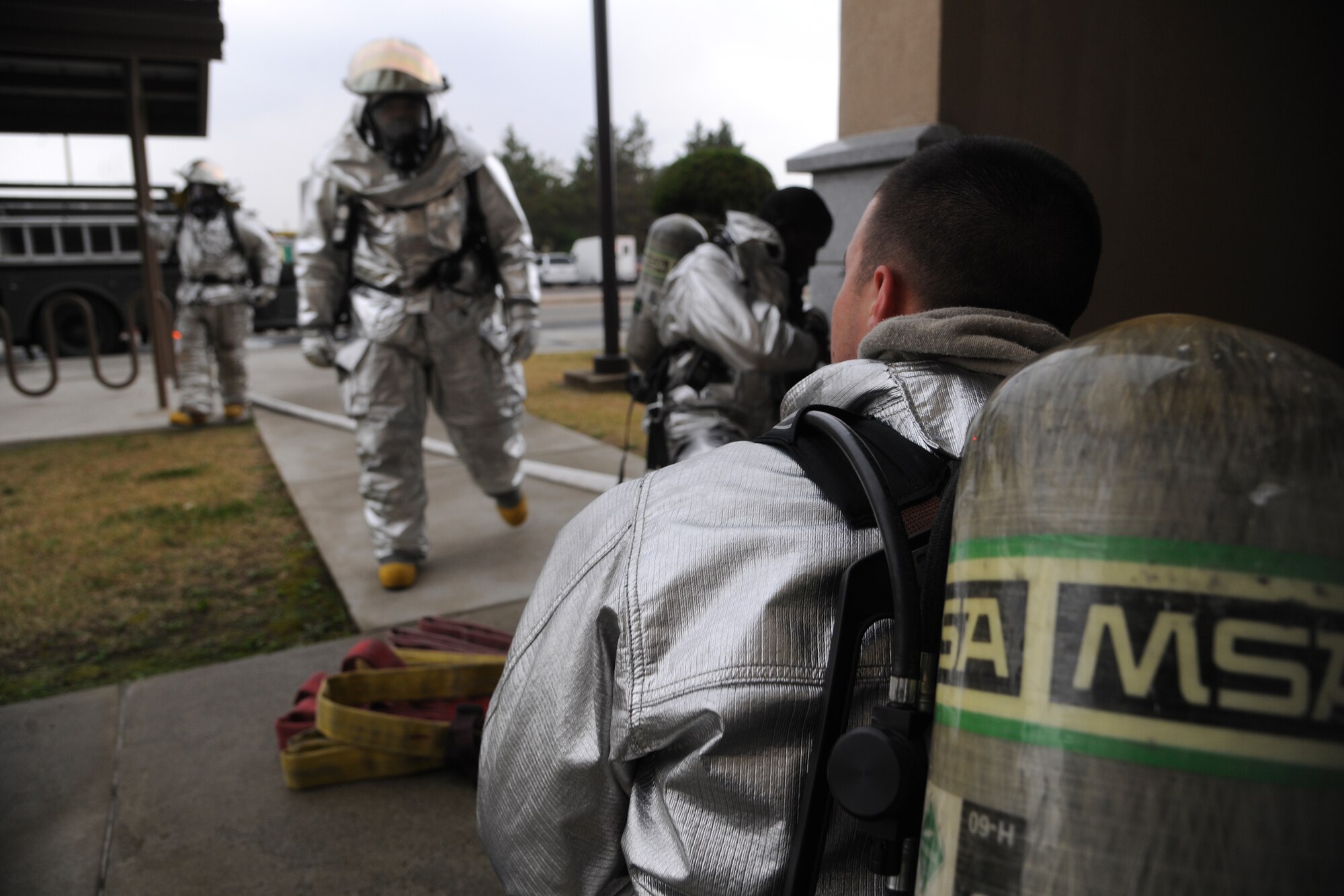 Firefighters from the 8th Civil Engineer Squadron gear up before entering the base theater during a scenario that the base theater was on fire at Kunsan Air Base, Republic of Korea, Oct. 24, 2011. The Exercise Evaluation Team scenarios included a full spectrum of events, keeping the wing fully engaged around the clock as maintainers launched aircraft, security forces defended the base and firefighters responded to a multitude of emergency situations. (U.S. Air Force photo by Staff Sgt. Rasheen Douglas/Released)