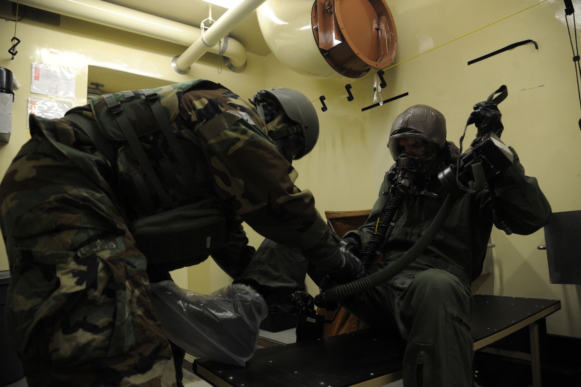 Capt. John Powers, 80th Fighter Squadron pilot, receives help from Senior Airman Jeffrey Wurst, 8th Operations Support Squadron aircrew flight equipment technician, in getting out of his decontaminated clothing during a simulated scenario of decontaminating a pilot at Kunsan Air Base, Republic of Korea, Oct. 24, 2011. The Exercise Evaluation Team scenarios included a full spectrum of events, keeping the wing fully engaged around the clock as maintainers launched aircraft, security forces defended the base and firefighters responded to a multitude of emergency situations. (U.S. Air Force photo by Staff Sgt. Rasheen Douglas/Released)