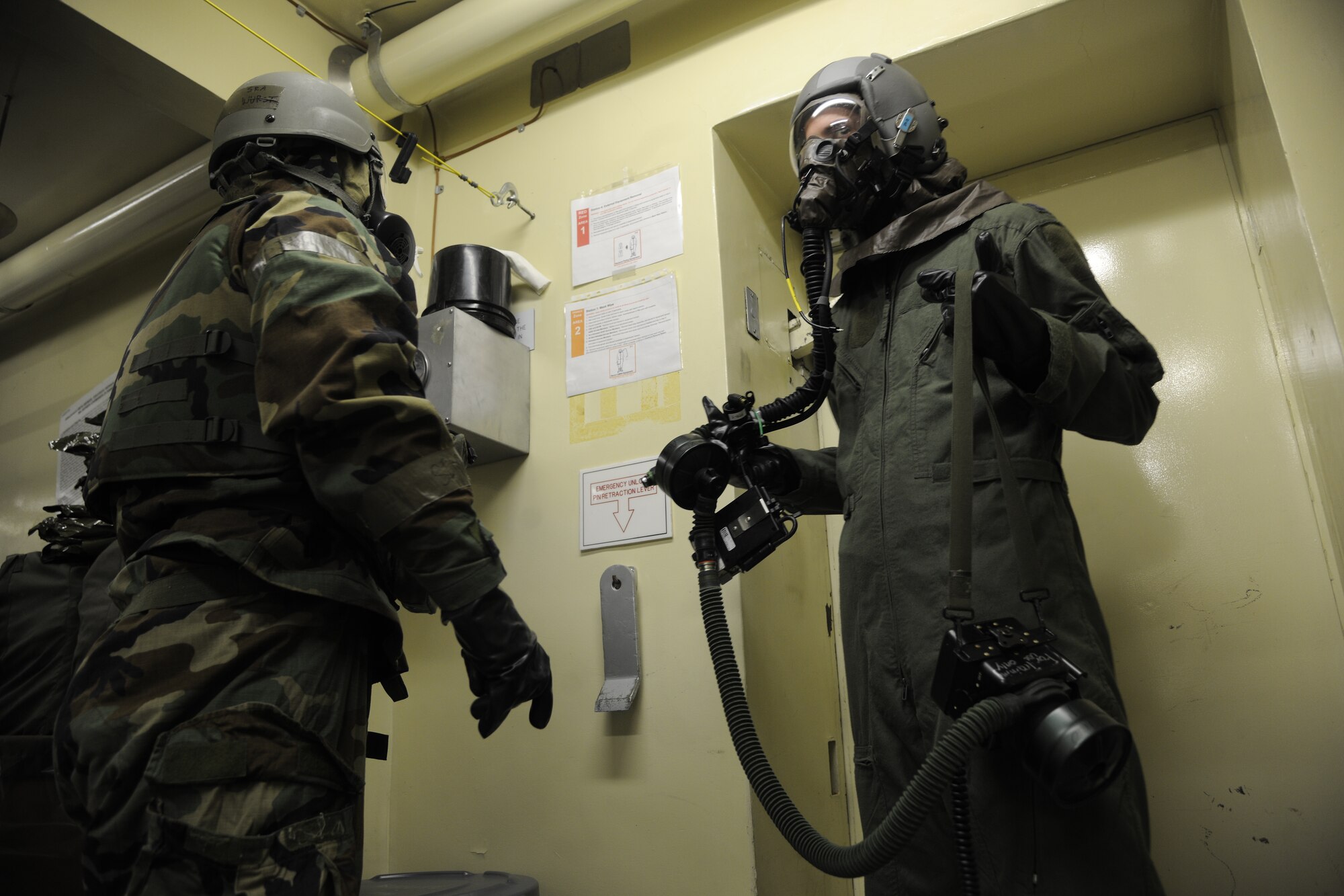 Senior Airman Jeffrey Wurst, 8th Operations Support Squadron aircrew flight equipment technician, explains decon procedures to Capt. John Powers, 80th Fighter Squadron pilot, during a simulated scenario of decontaminating a pilot at Kunsan Air Base, Republic of Korea, Oct. 24, 2011. The Exercise Evaluation Team scenarios included a full spectrum of events, keeping the wing fully engaged around the clock as maintainers launched aircraft, security forces defended the base and firefighters responded to a multitude of emergency situations. (U.S. Air Force photo by Staff Sgt. Rasheen Douglas/Released)