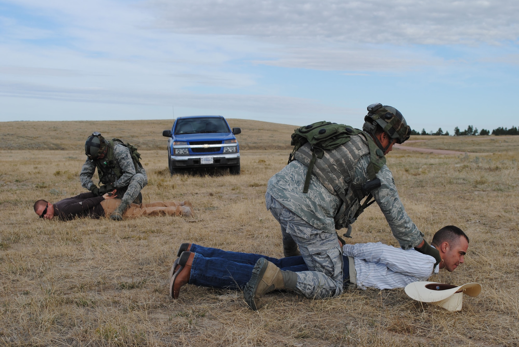 Senior Airmen Nicholas Kirschbaum, left, and Jeremy Lamphear, both convoy response force members with the 741st Missile Security Forces Squadron detain two members of F.E. Warren's Op For team, posing as aggressive farmers during a scenario at Camp Guernsey. (U.S. Air Force photo/Airman 1st Class Katrina Heikkinen)