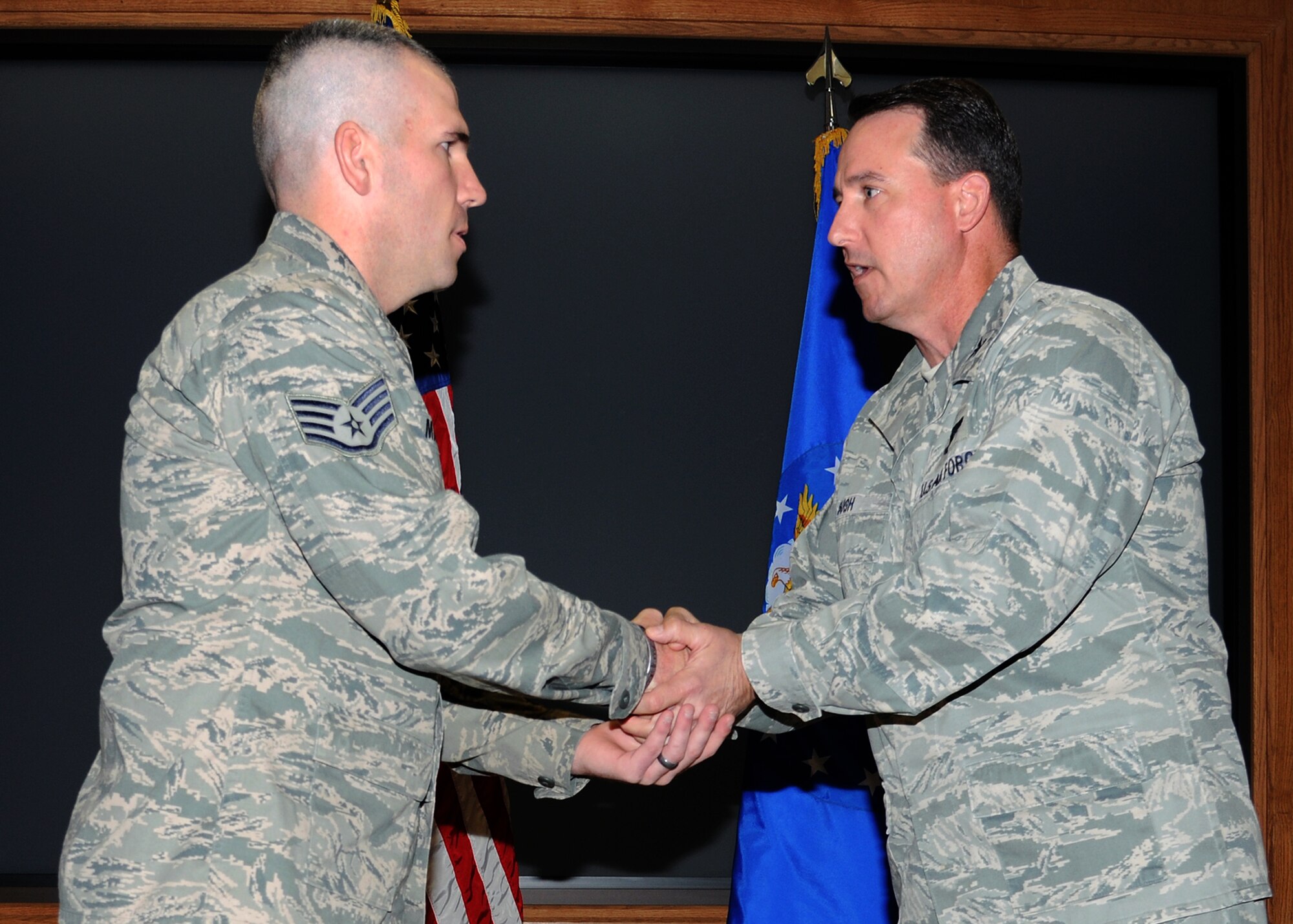 U.S. Air Force Col. Tim Bush, 319th Air Base Wing commander, (right) presents Staff Sgt. Bryant Martin, 319th Security Forces Squadron, with a commander’s coin on Oct. 26 at Grand Forks Air Force Base, N.D. Bryant is credited with helping a 5-year-old base family member who stopped breathing during a seizure on base Oct. 23. (U.S. Air Force photo/Airman 1st Class Ashley Taylor)
