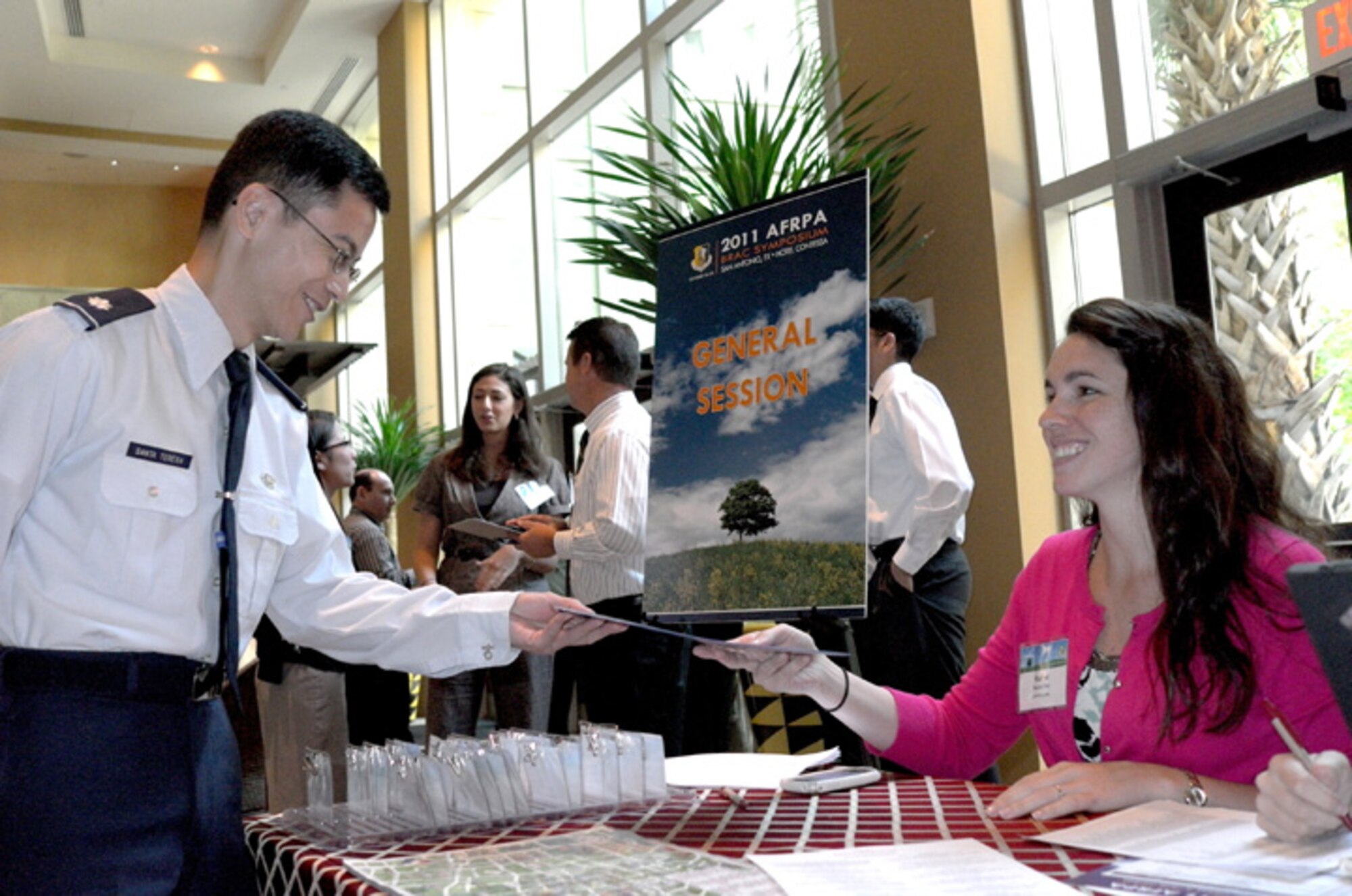 Lt. Col. J. Emmanuel I. Santa Teresa is greeted by Ms. Rachel Fish as he registers at the AFRPA 2011 BRAC Symposium in San Antonio, Texas. Lt. Col. Santa Teresa is deputy chief of environmental law at the Air Force Field Support Center based in San Antonio.