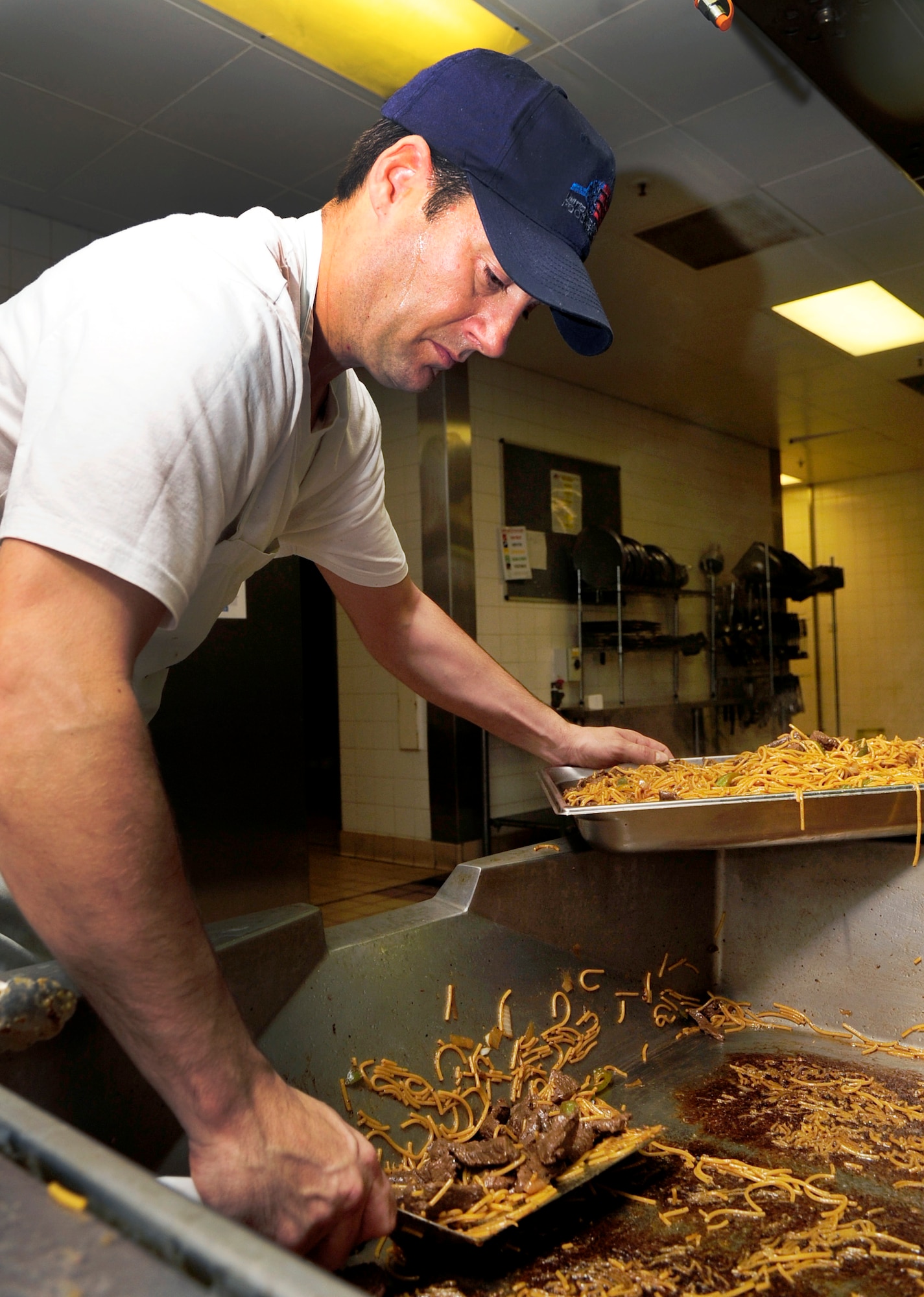 RAF MILDENHALL, England – Brian Simms, 100th Force Support Squadron cook, transfers freshly cooked Yakisoba noodles to a serving tray at the Gateway Dining Facility here Oct. 25, 2011. The noodles were cooked in preparation for the dinner meal. (U.S. Air Force photo/Senior Airman Ethan Morgan)