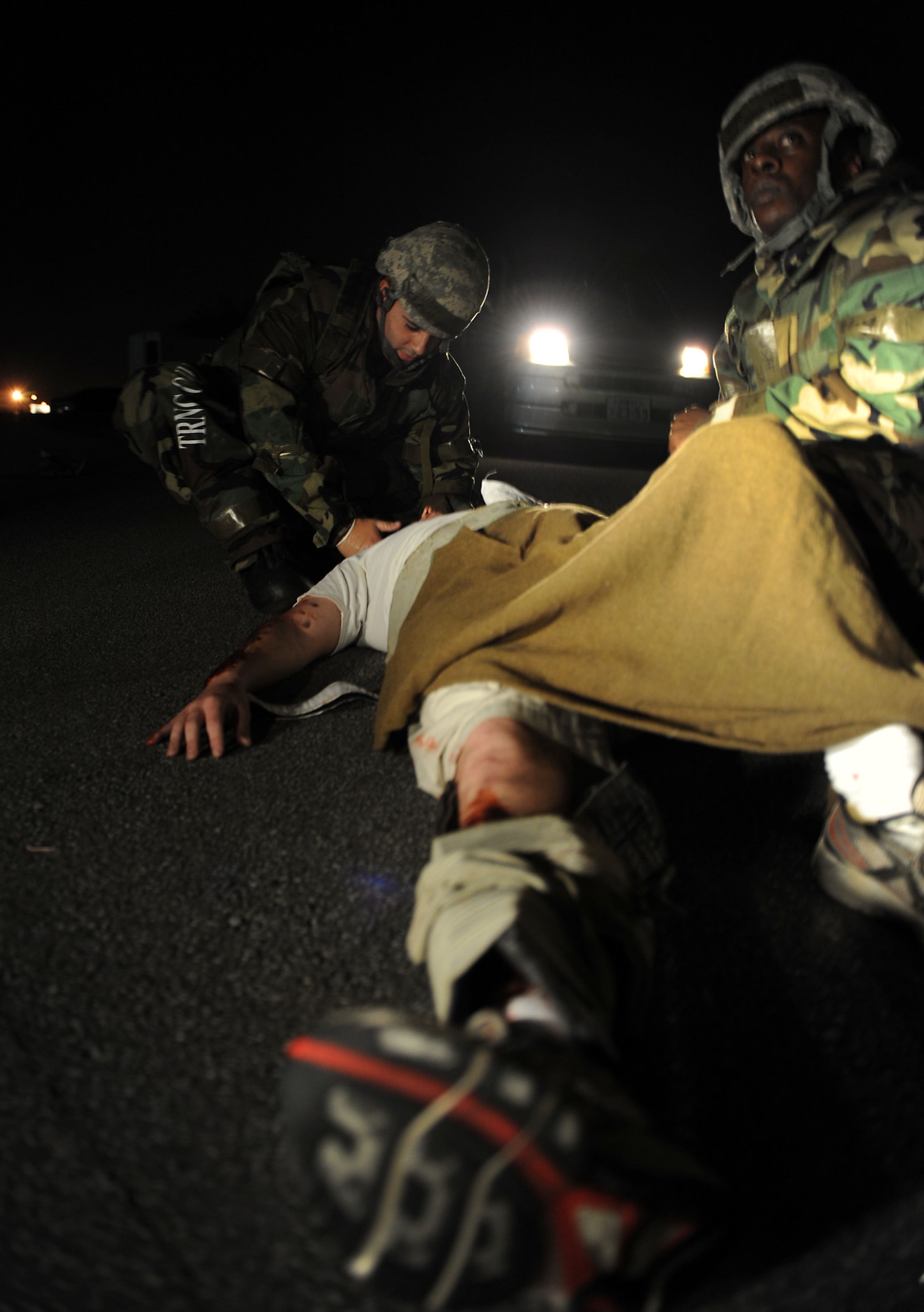 Capt. Jeffrey Drake, 18th Aeromedical Evacuation Squadron operations support flight commander, steadies the head of a moulage victim, while Tech. Sgt. Jaime Faison, 18th AES aeromedical evacuation technician, keeps a lookout for emergency responders during local operational readiness exercise Beverly High 12-1 at Kadena Air Base, Japan, Oct. 26. Self-aid and buddy care training scenarios like these are conducted each LORE to keep Kadena's Airmen trained to respond to similar real-world scenarios. (U.S. Air Force photo/ Senior Airman Sara Csurilla/ released)