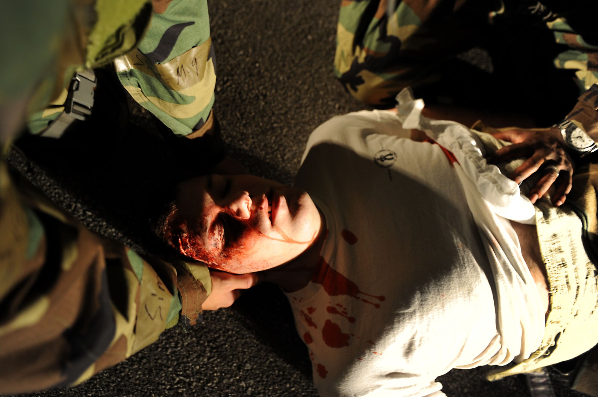 U.S. Air Force Airman 1st Class Beau Shelley, 18th Equipment Maintenance Squadron armament apprentice and "victim" to a car accident, is aided by Airmen from the 18th Aeromedical Evacuation Squadron during local operational readiness exercise Beverly High 12-1 at Kadena Air Base, Japan, Oct. 26. The realistic moulage wounds on Shelley give an extra sense of urgency during exercise scenarios he and other simulated victims are needed for. (U.S. Air Force photo/Senior Airman Sara Csurilla/released)