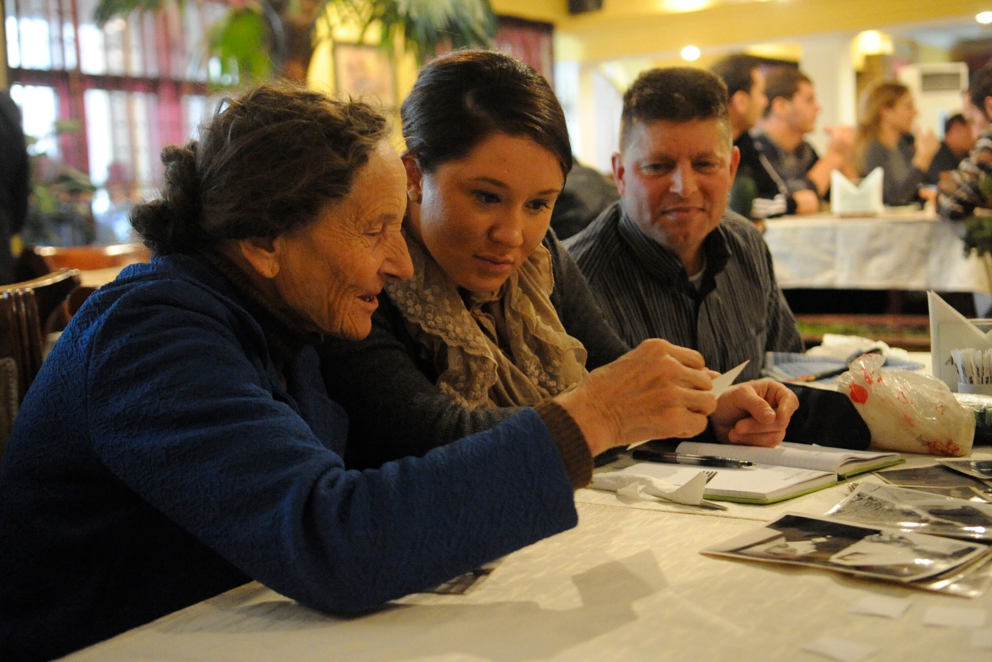 Vera Volf shares photos with Army Spc. Jayna Marks-Rench and Tech. Sgt. Timothy Dahnke during a lunch with three Babushkas in Bishkek, Kyrgyzstan, Oct. 25. Babushka is the Russian word for grandmother. Members of the Manas Area Benefit Outreach Society travel to Bishkek twice a month to spend time with the three ladies. Marks-Rench is the MABOS vice president and Babushka focus group leader. She is deployed to the Transit Center at Manas as a customs official from the Minnesota Army Reserves, and is a native of Rochester, Minn. Dahnke is deployed to the 376th Expeditionary Force Support Squadron as the NCO in charge of Pete’s Place from the Wisconsin Air National Guard. (U.S. Air Force photo/Tech. Sgt. Tammie Moore)
