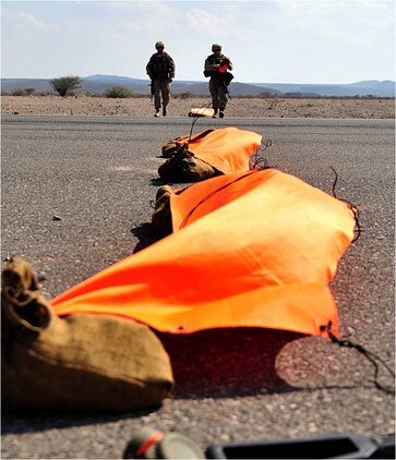 U.S. Marines Corporals Adam Osley, navigation aid technician, and Bryan Reilly, air traffic controller, both with the Marine Air Traffic Control Mobile Team, 22nd Marine Expeditionary Unit, finish checking the aircraft touchdown area designation panels to ensure they are secured to the asphalt at Chabelley Airfield, Djibouti, October 27. Osley is originally from Biloxi, Mississippi, and Reilly is from Middlesex, New Jersey. During the day, the MMT uses panels to mark the austere landing zone.