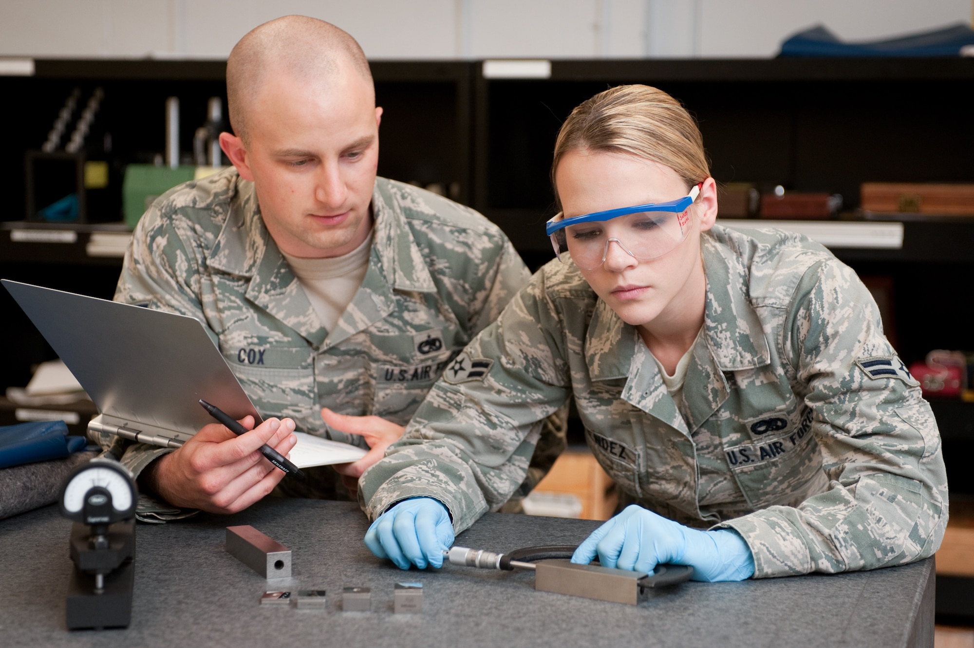 Airman First Class Kourtnie Melendez, a calibration technician with the 60th Maintenance Squadron's Preceision Measurement Equipment Laboratory, uses a stainless steel gauge block to measure a micrometer, while Staff Sgt. John Cox, a quality assurance evaluator, observes her work. PMEL fine tunes countless pieces of equipment, like this micrometer that is used by a jet engine shop belonging to the California Air National Guard. (U.S. Air Force photo/ Ken Wright)
