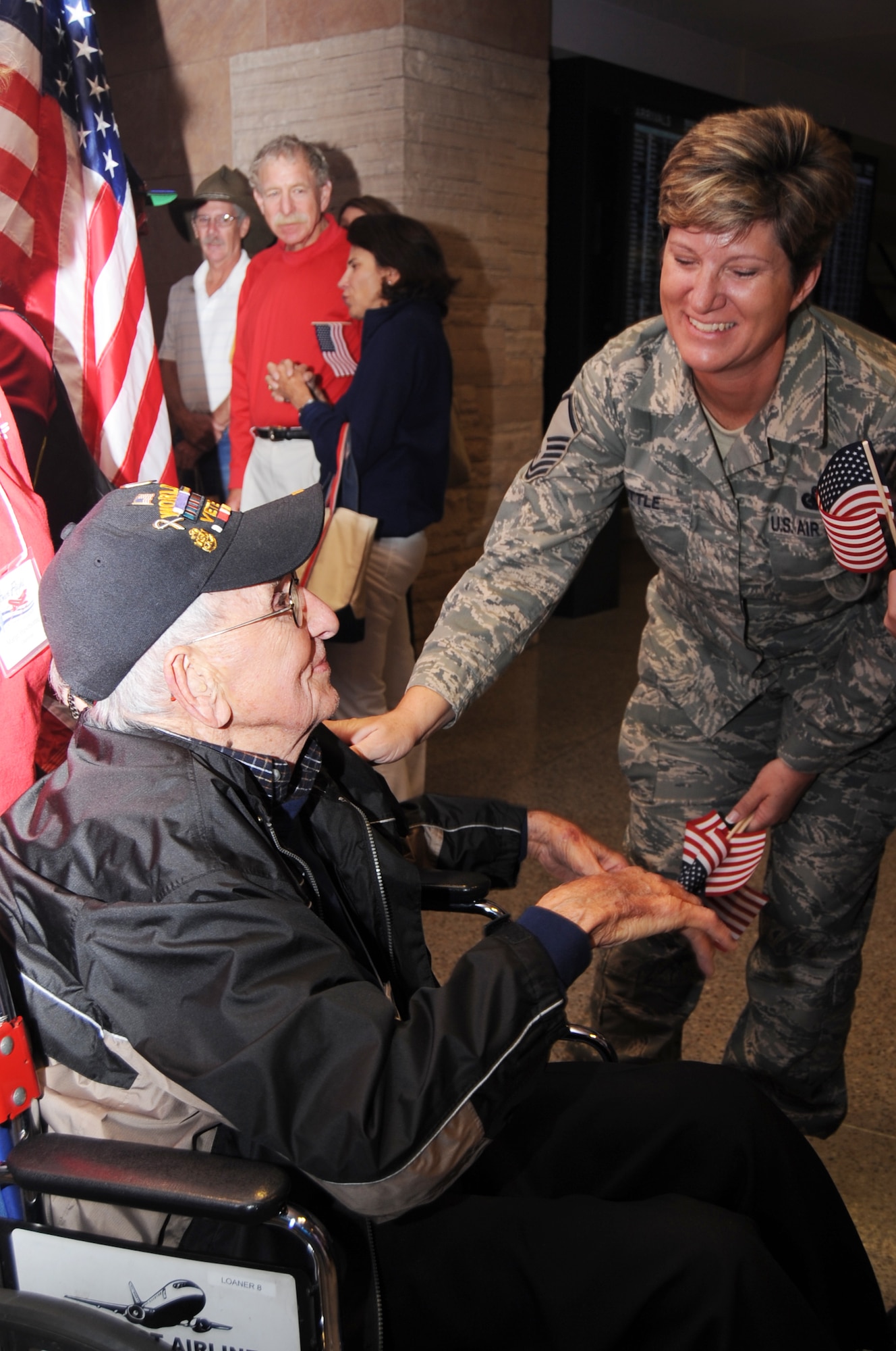 U.S. Air Force Master Sgt. April Little, 355th Force Support Squadron, welcomes home Mr. Robert Berni, retired Navy World War II veteran, from his trip to Washington, D.C., with Honor Flight Tucson at Tucson International Airport Oct. 21, 2011. Honor Flight Tucson is powered by volunteers that perform a plethora of duties from travel agent to travel companion. The organization sponsors war veterans on visits to Washington, D.C., where they are escorted to the commemorative memorials by their travel companions and military volunteers. There veterans can view monuments dedicated to the wars they fought and the fallen comrades that they fought alongside. (U.S. Air Force photo by Airman 1st Class Saphfire Cook/Released)