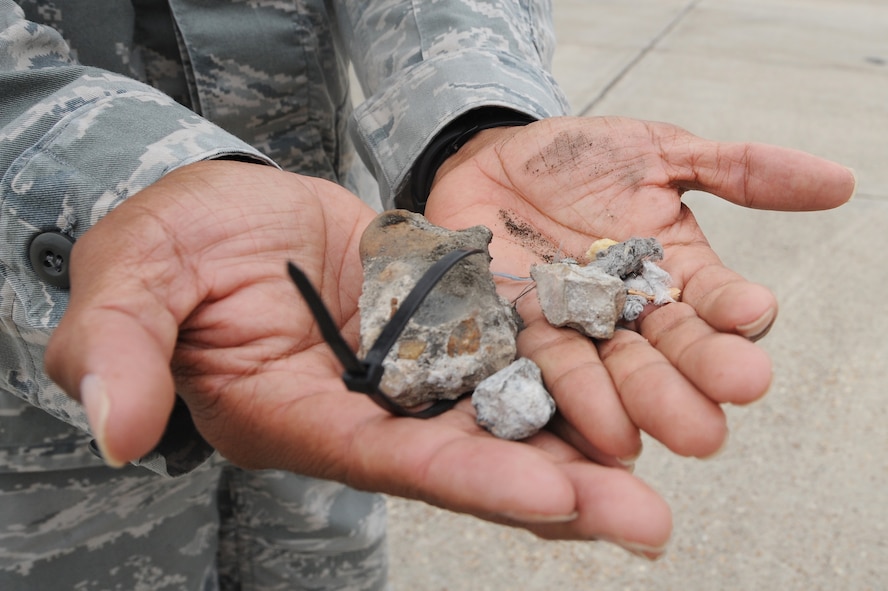 U.S. Air Force Tech. Sgt. Thomas Gibson, 75th Aircraft Maintenance Unit lead engine technician, displays scraps found on the flight line during a FOD walk at Moody Air Force Base, Ga., Oct. 27, 2011. Gibson showed the scraps to other flight line members to remind them that certain items can be hazardous during takeoff. Loose gravel, metal, trash and rocks are all types of objects that can potentially damage aircraft. (U.S. Air Force photo by Airman 1st Class Olivia Dominique/Released)