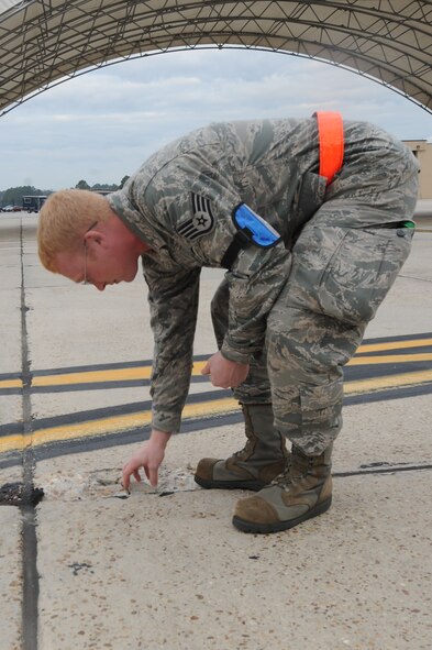 U.S. Air Force Staff Sgt. Daniel Pingley, 75th Aircraft Maintenance Unit avionics, retrieves debris found during a Foreign Object Debris (FOD) walk at Moody Air Force Base, Ga., Oct. 27, 2011. FOD walks are completed daily to ensure the flight line is clear of objects that could be picked up during takeoff and cause damage to aircraft. (U.S. Air Force photo by Airman 1st Class Olivia Dominique/Released)