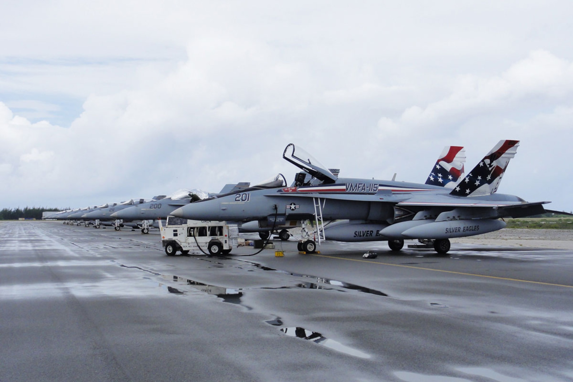 WAKE ISLAND AIRFIELD, Mid-Pacific -- A row of F-18A Hornets from VMFA-115, based out of Marine Corps Air Station Beaufort, S.C., sits on the ramp at Wake Island Airfield during a recent TRANSPAC from Hawaii to MCAS Iwakuni in Japan.  The plane in the front with painted vertical stabilizers is the unit’s flagship, commonly called a “pretty bird” by crewmembers. (U.S. Air Force photo by Capt. Amy Hansen)