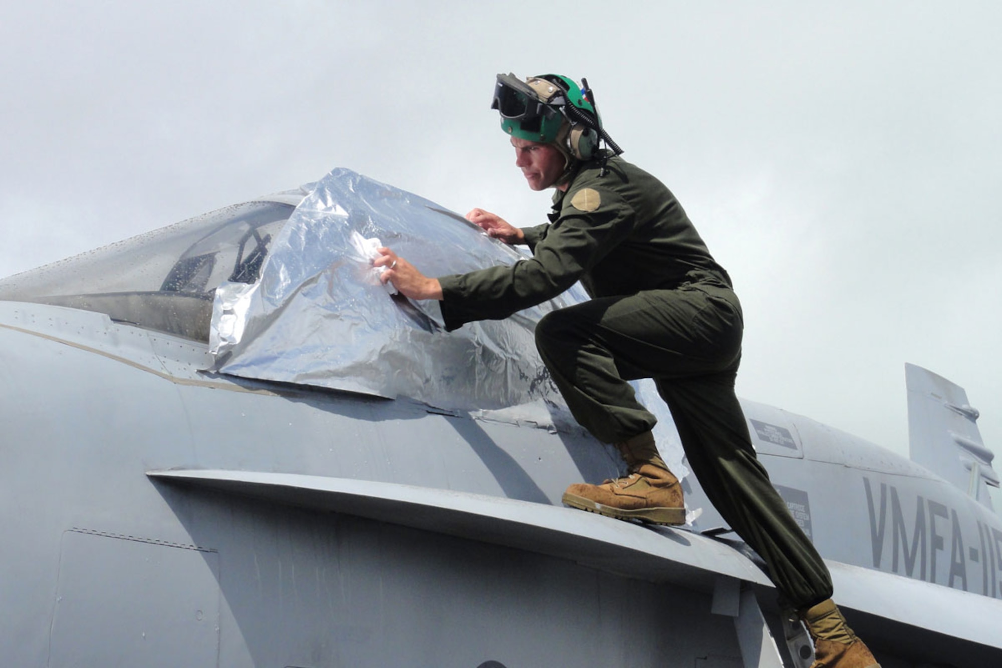 WAKE ISLAND AIRFIELD, Mid-Pacific -- Sgt. Joshua Upton, VMFA-115 airframe mechanic, wipes rain off a sheet covering wet paint.  The 20-30 maintenance personnel which participate in the unit’s TRANSPAC missions are handpicked due to their ability to keep the jets flying for the 10,000 mile trip from South Carolina to Japan. (U.S. Air Force photo by Capt. Amy Hansen)
