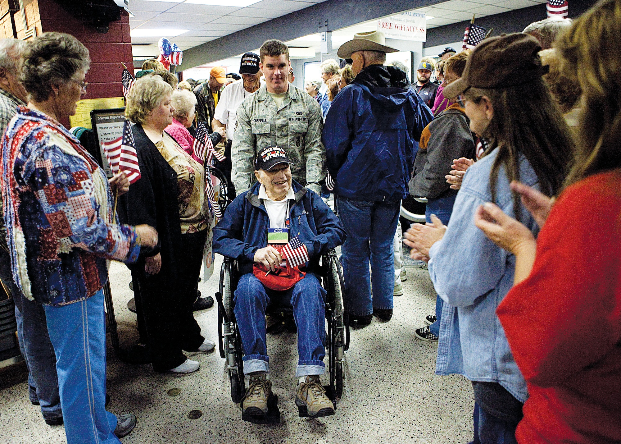 Senior Airman Jarrick Chappell, 90th Missile Maintenance Squadron, helps a World War II veteran navigate through the Cheyenne Regional Airport Oct. 12. Veterans were flown to Washington D.C. the day prior as part of the final Honor Flight. (U.S. Air Force photo by Matt Bilden)